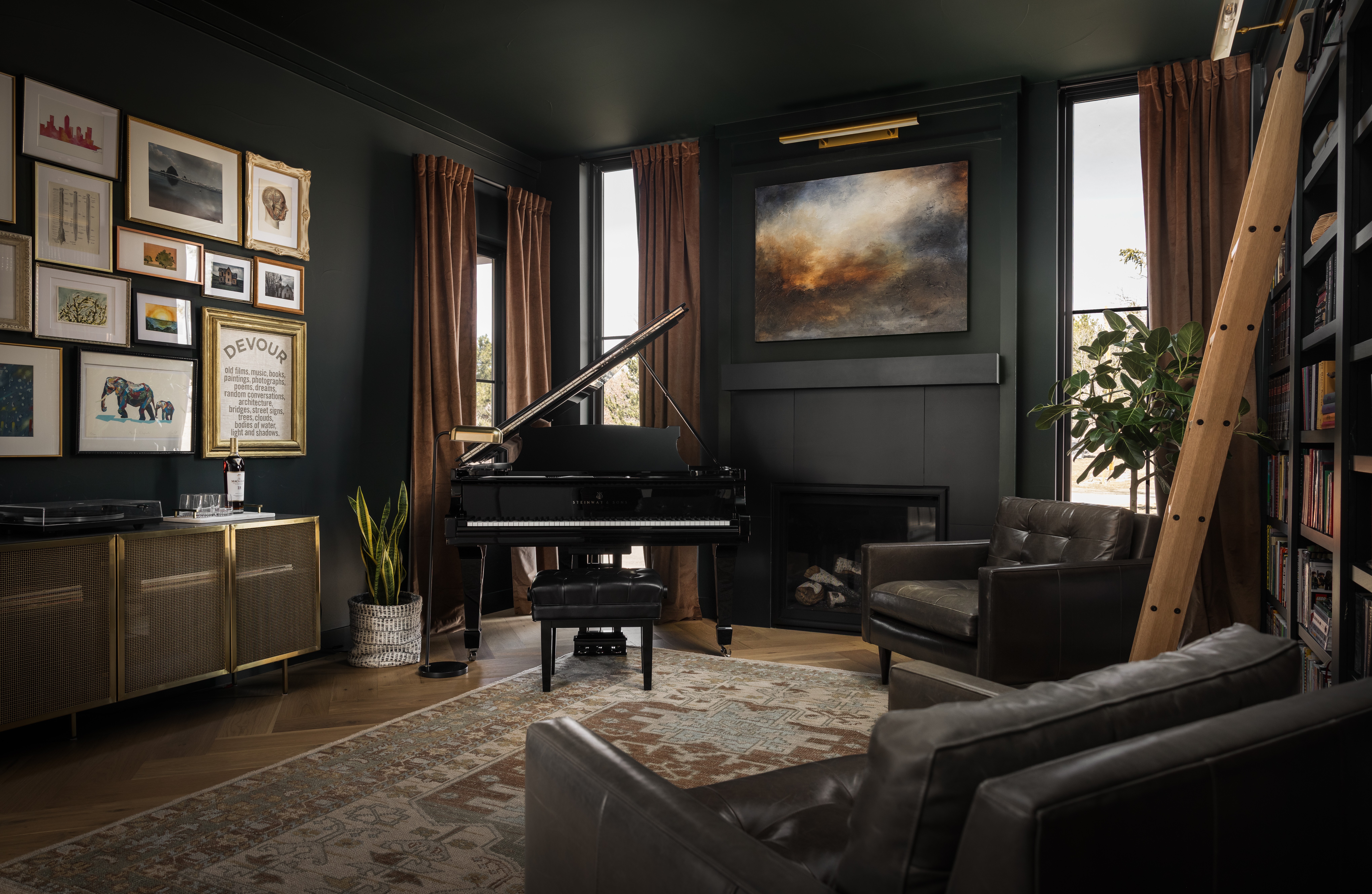 Living room with grand piano, armchair, sofa, framed artwork, bookshelf, and large window with curtains.