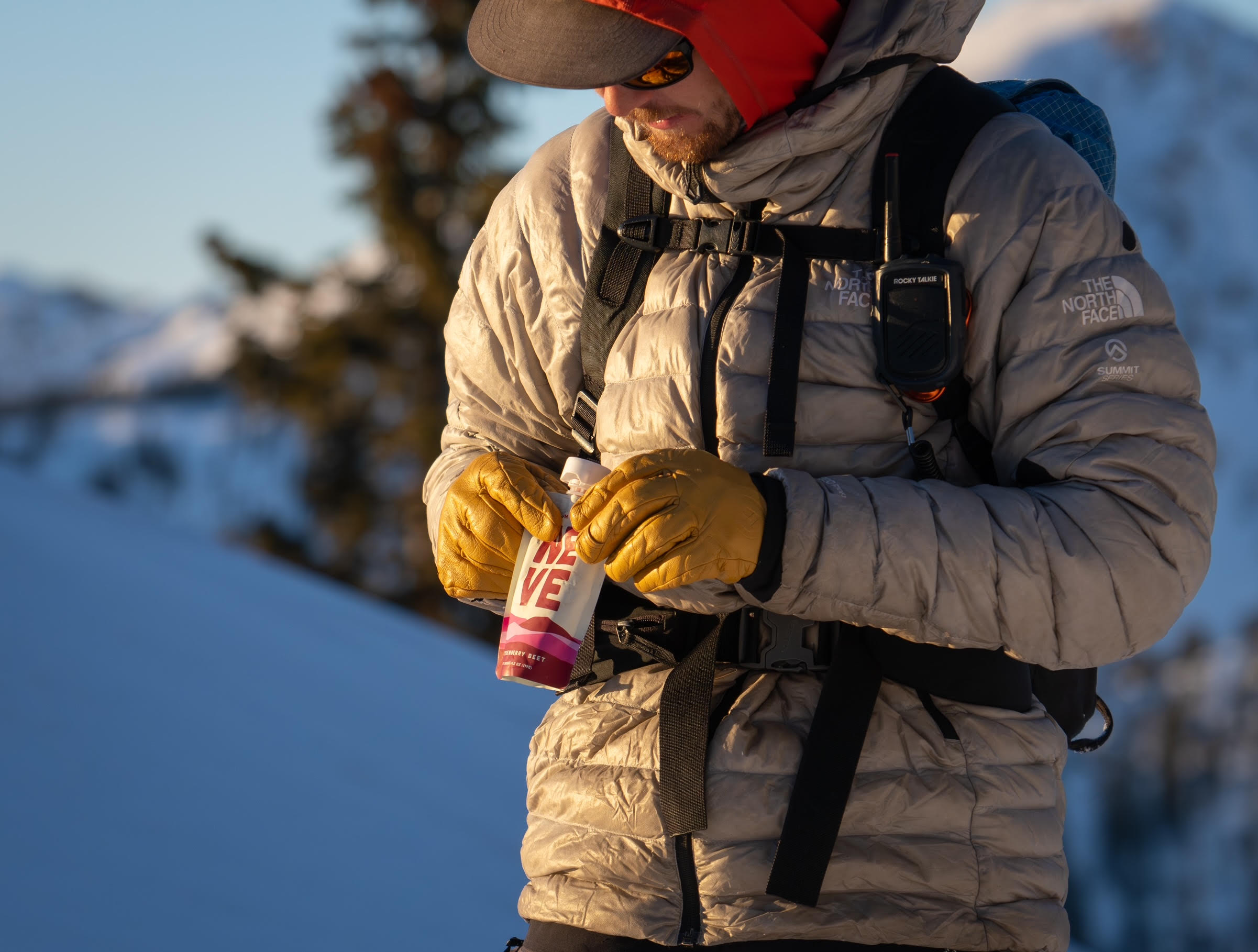 Person in winter clothing holding a small container outdoors in snowy landscape.