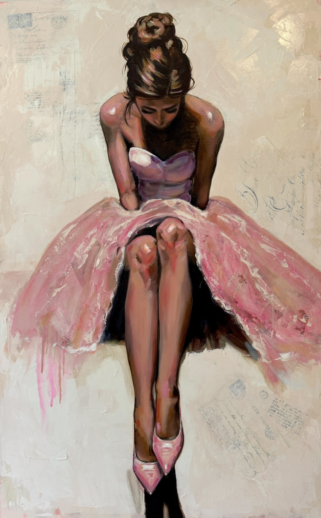 Young woman in pink dress sitting with legs crossed, looking down, against a plain background.