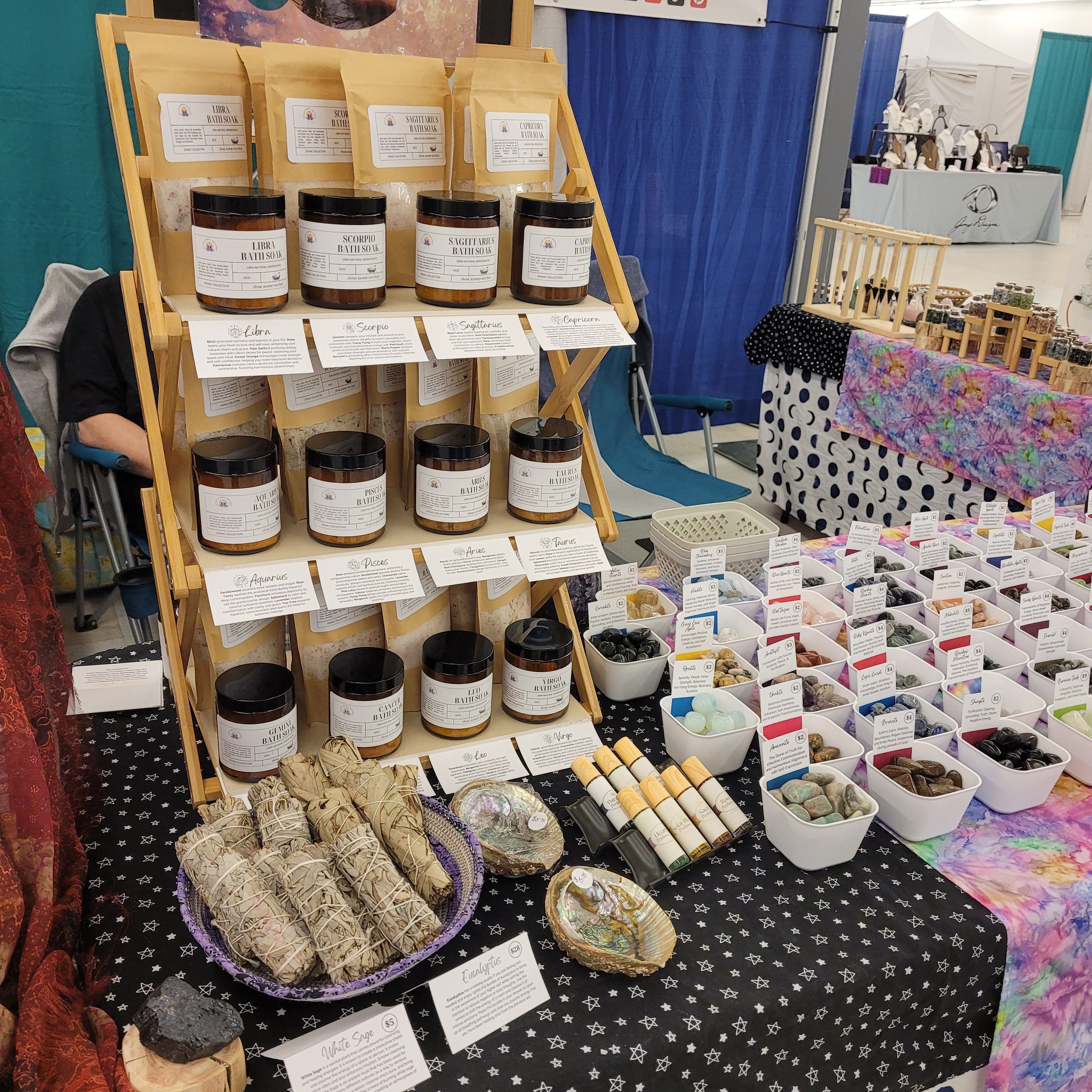 Display of jars, soap bars, and small containers on a black tablecloth at a market stall.
