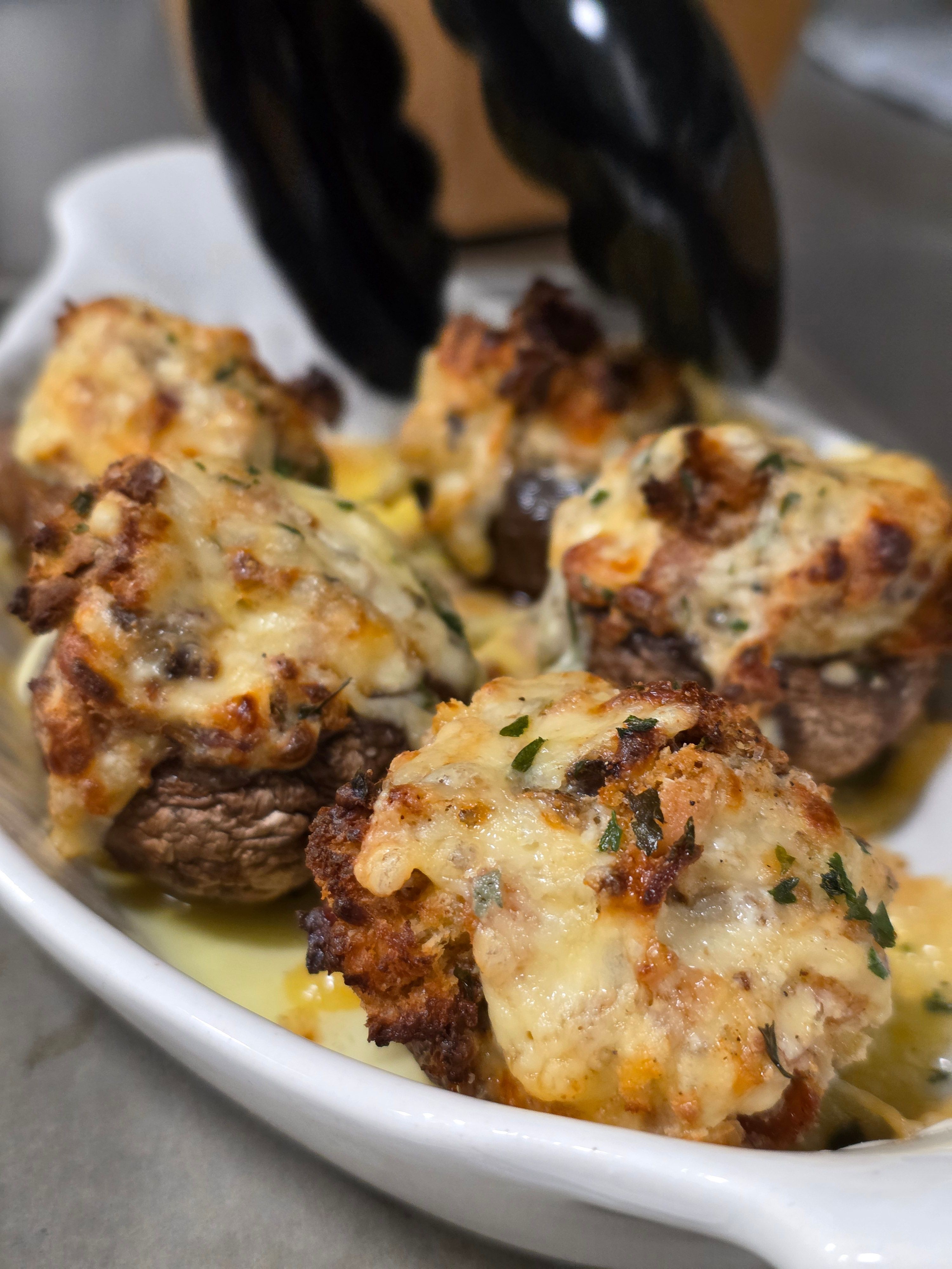 Baked dish with melted cheese, meat, and herbs in a white bowl, close-up view.