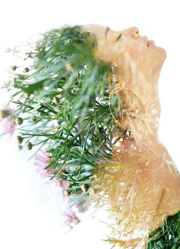 A woman with closed eyes and long hair, with green foliage and flowers overlapping her face and hair, against a white background.