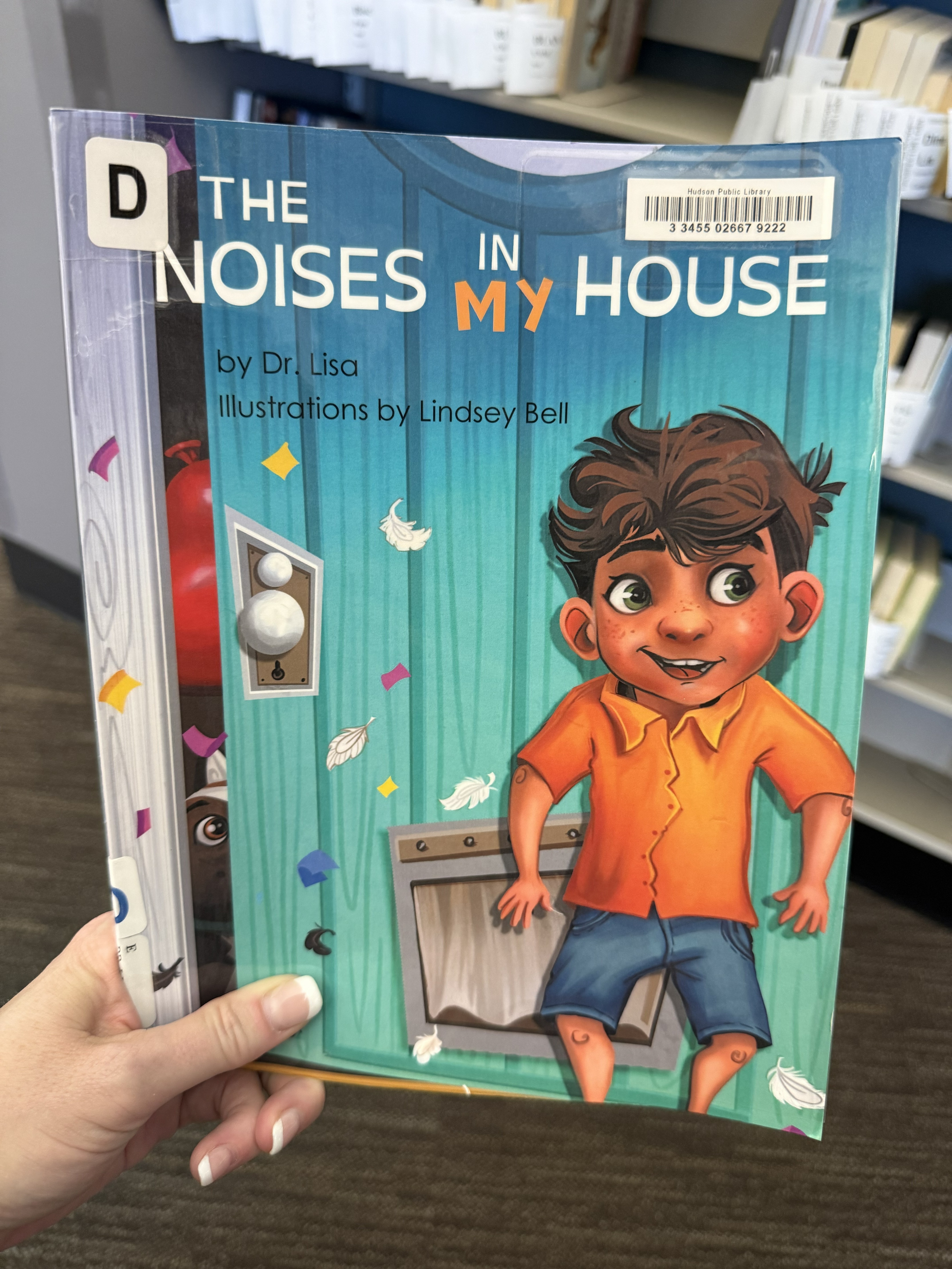Book cover showing a young boy with curly hair in an orange shirt and blue shorts standing in front of a door with a window, colorful confetti around him.