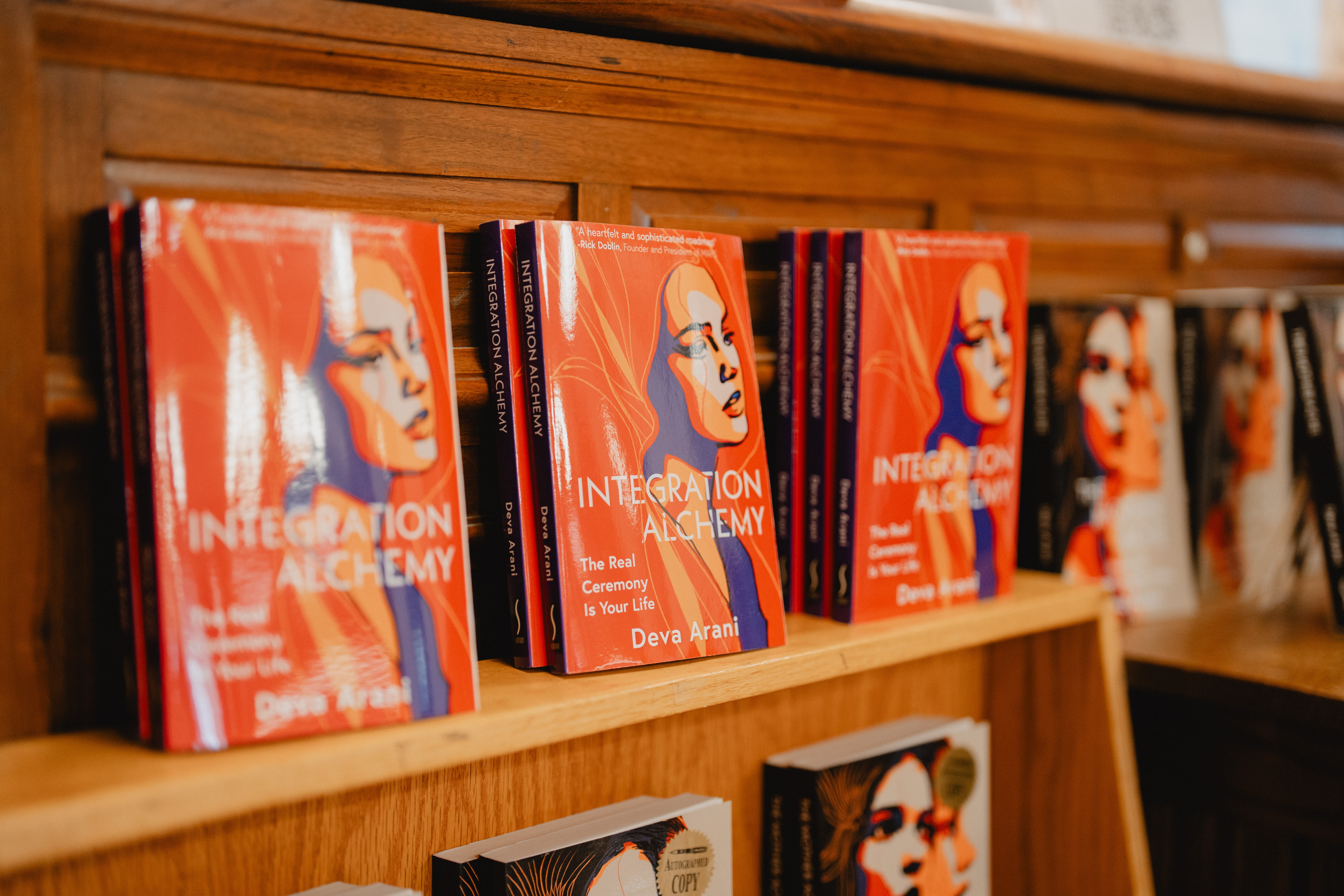 Books with orange covers on a wooden shelf, featuring a woman's face and the title 'Integration Academy'.