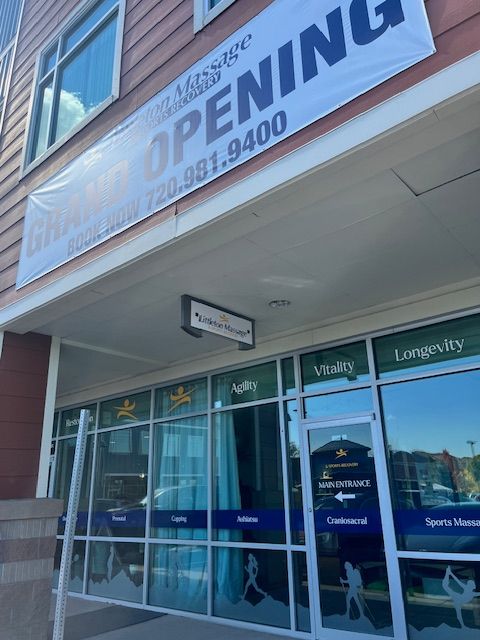 View of a building entrance with glass doors and windows, and a sign partially visible on the left side.