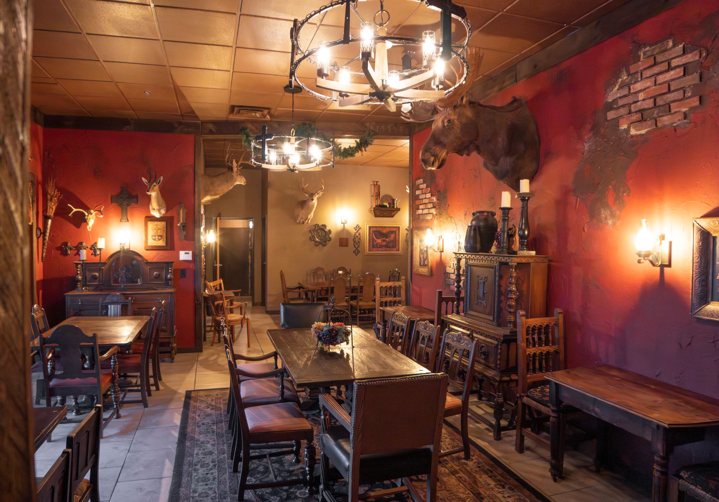 Interior of a cozy restaurant with wooden tables, chairs, warm lighting, and red and yellow walls.