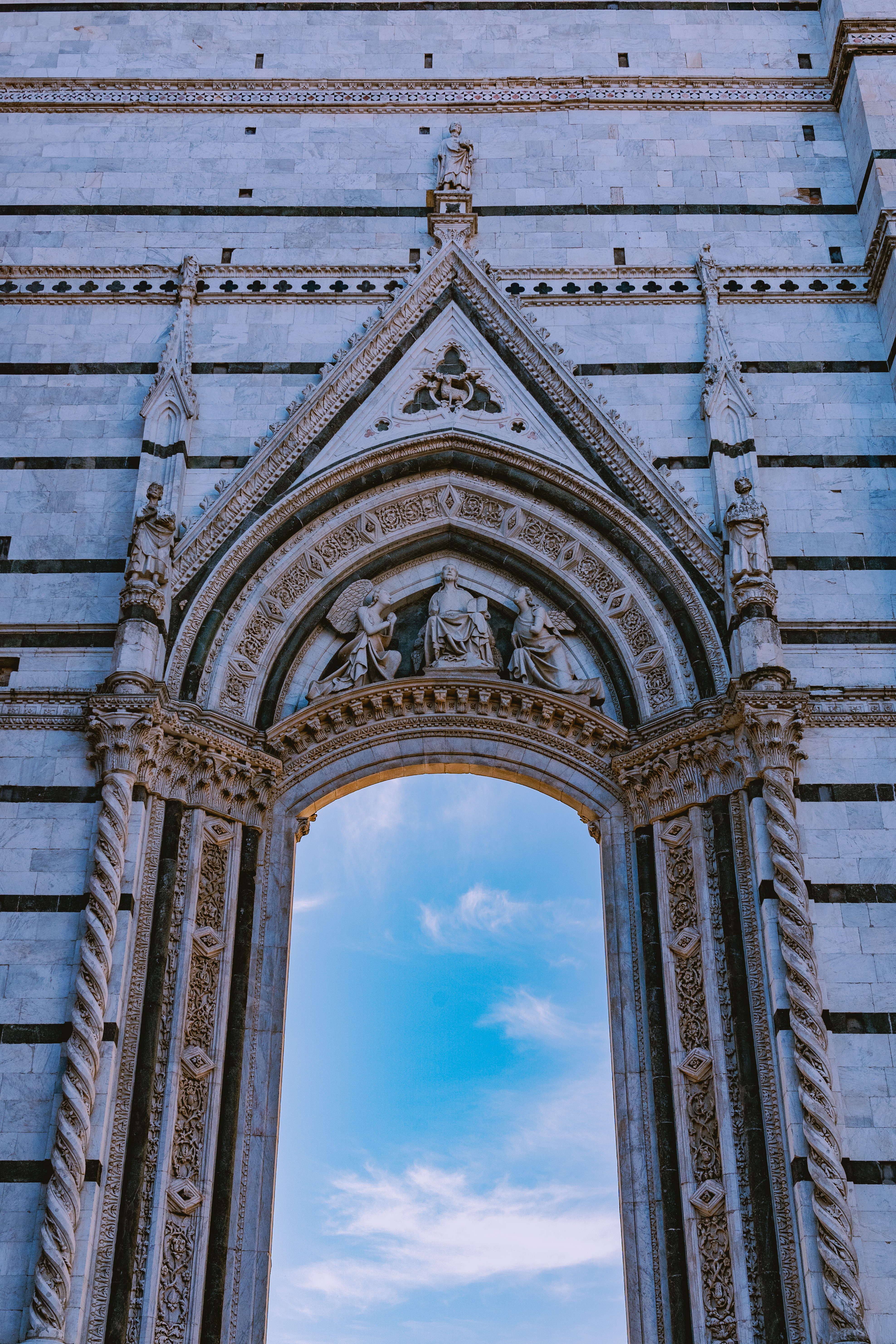 Ornate arched entrance with detailed carvings and a blue sky visible through the opening.