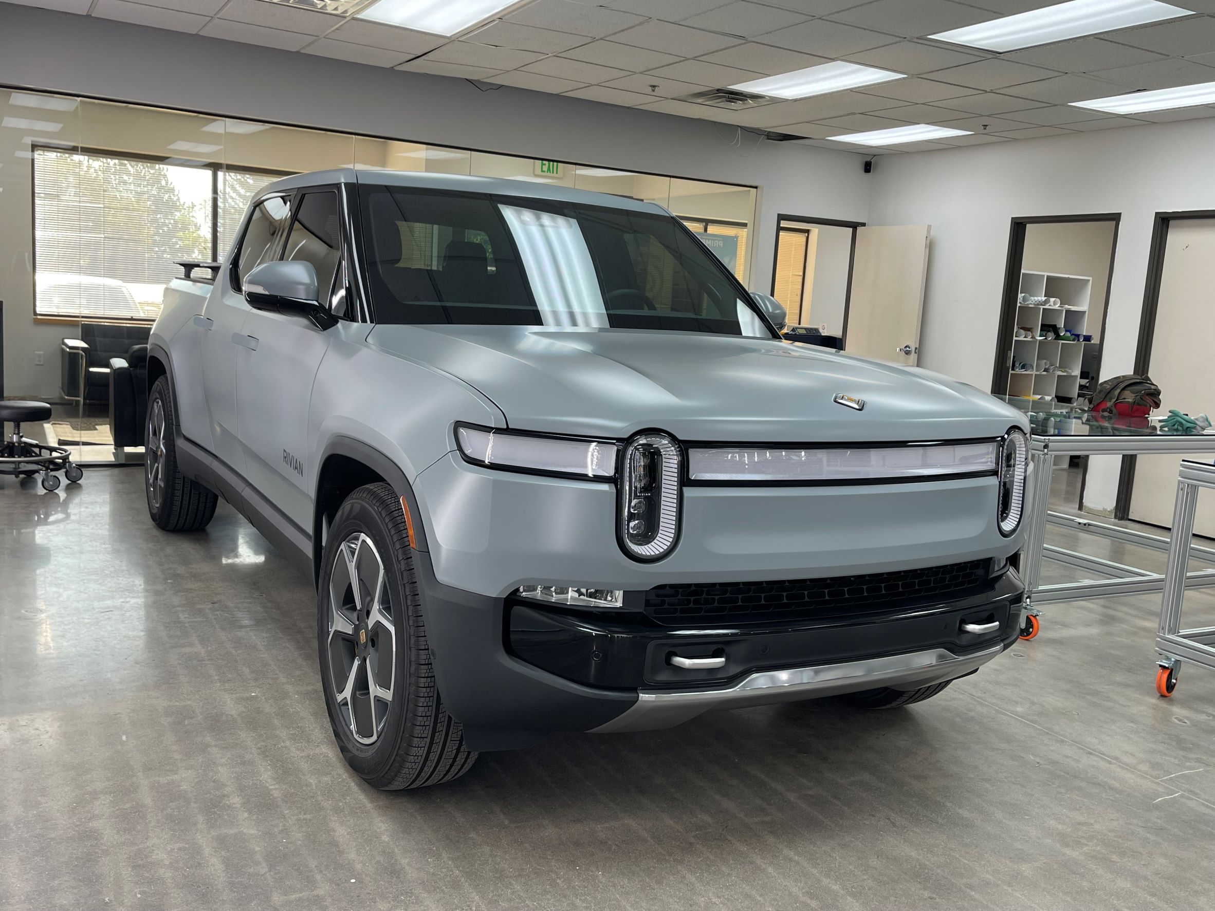 Silver SUV parked indoors with large windows and office furniture nearby.