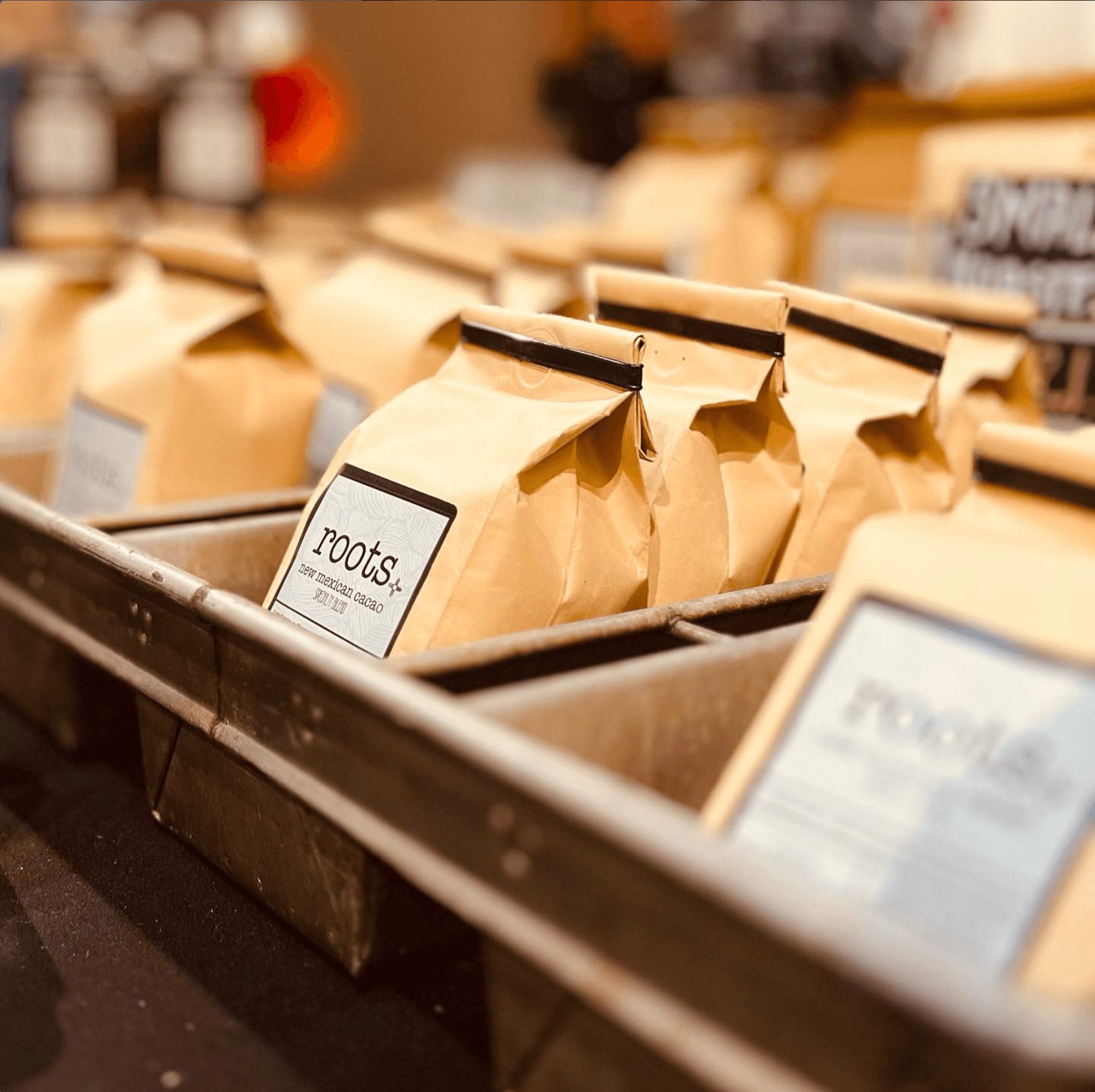 Bags of coffee on a display shelf in a store, with a blurred background of other products.