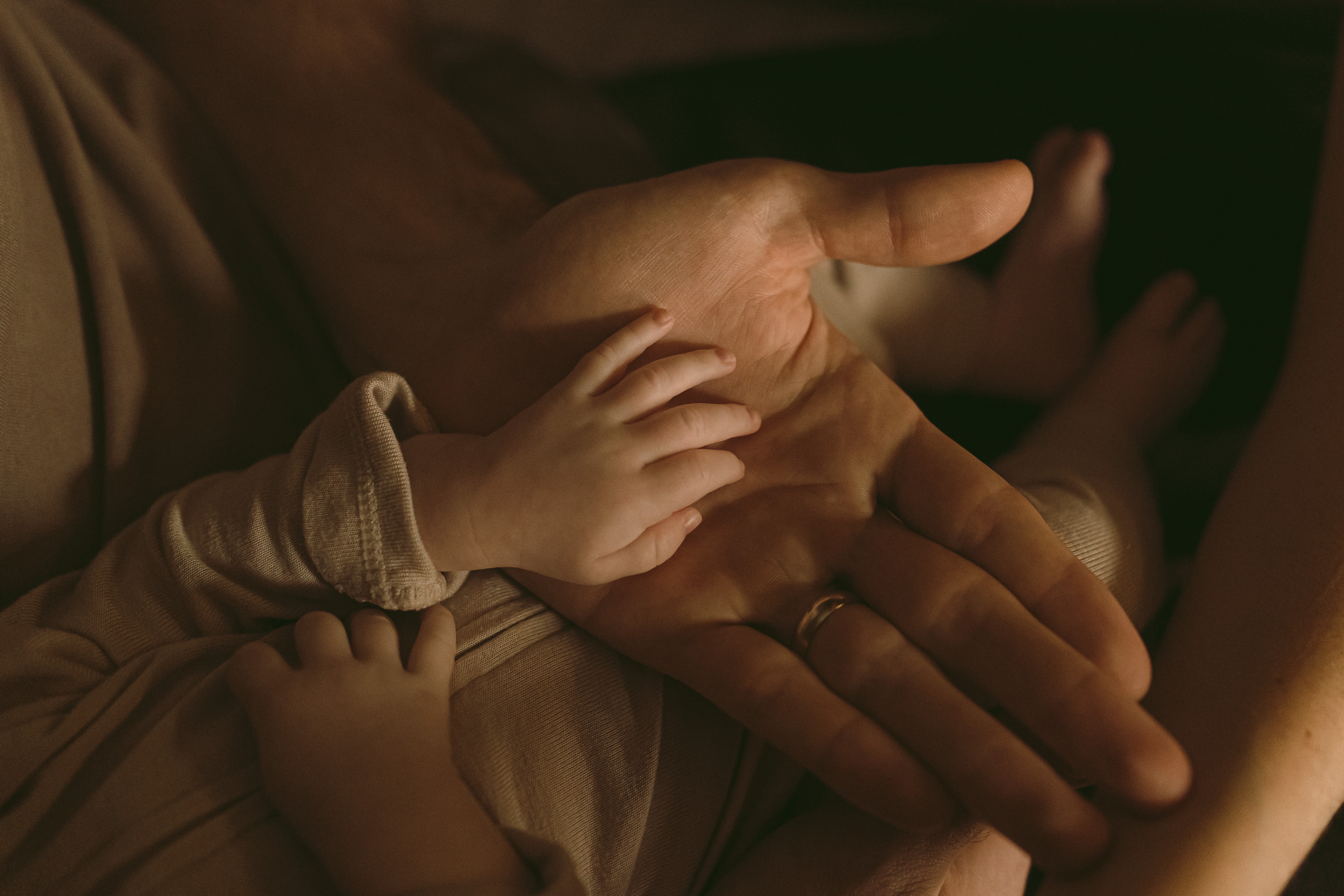 Close-up of a child's hand resting on an adult's hand, with a child's arm and part of their body visible.