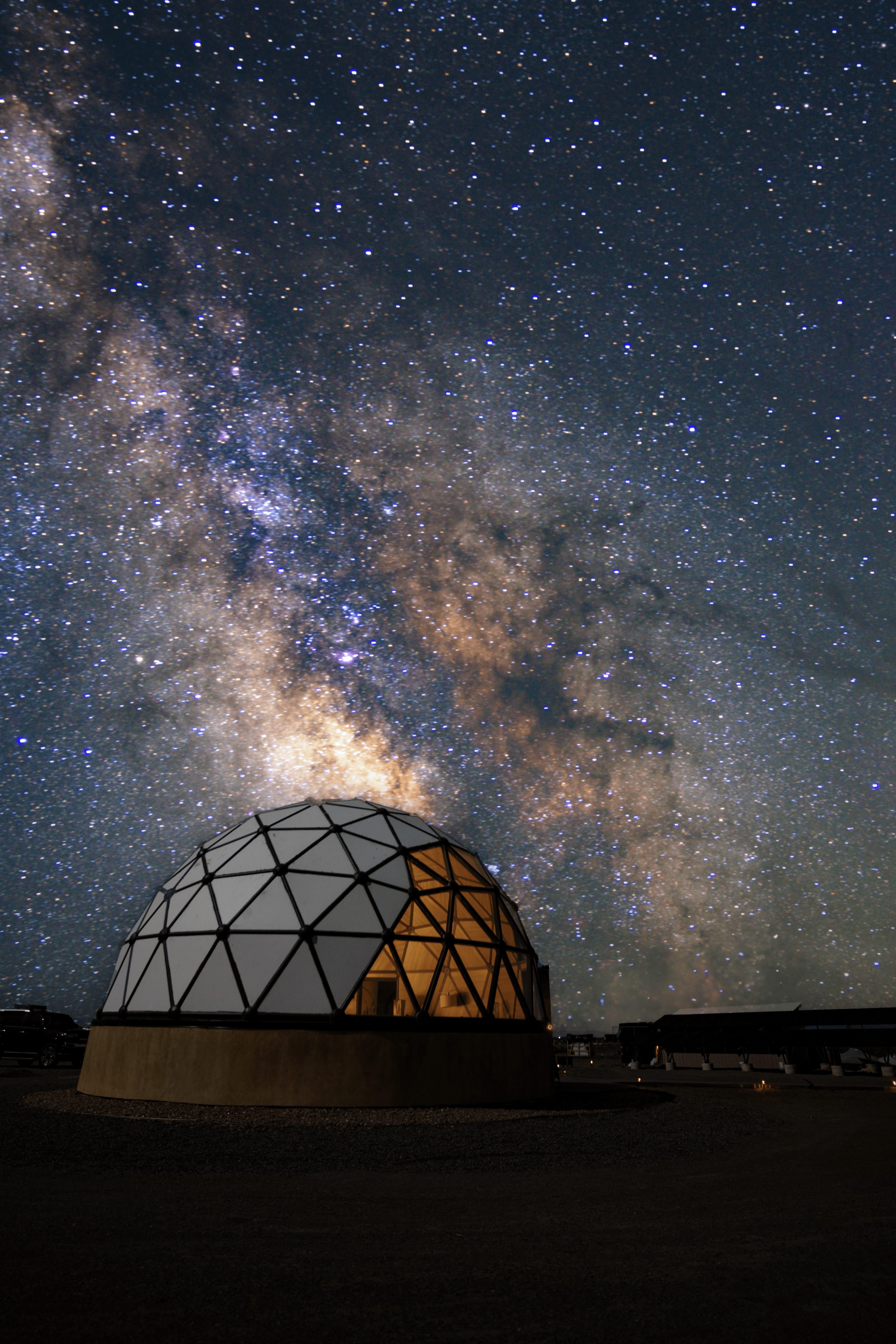 Night sky filled with stars and the Milky Way galaxy above a geodesic dome observatory.