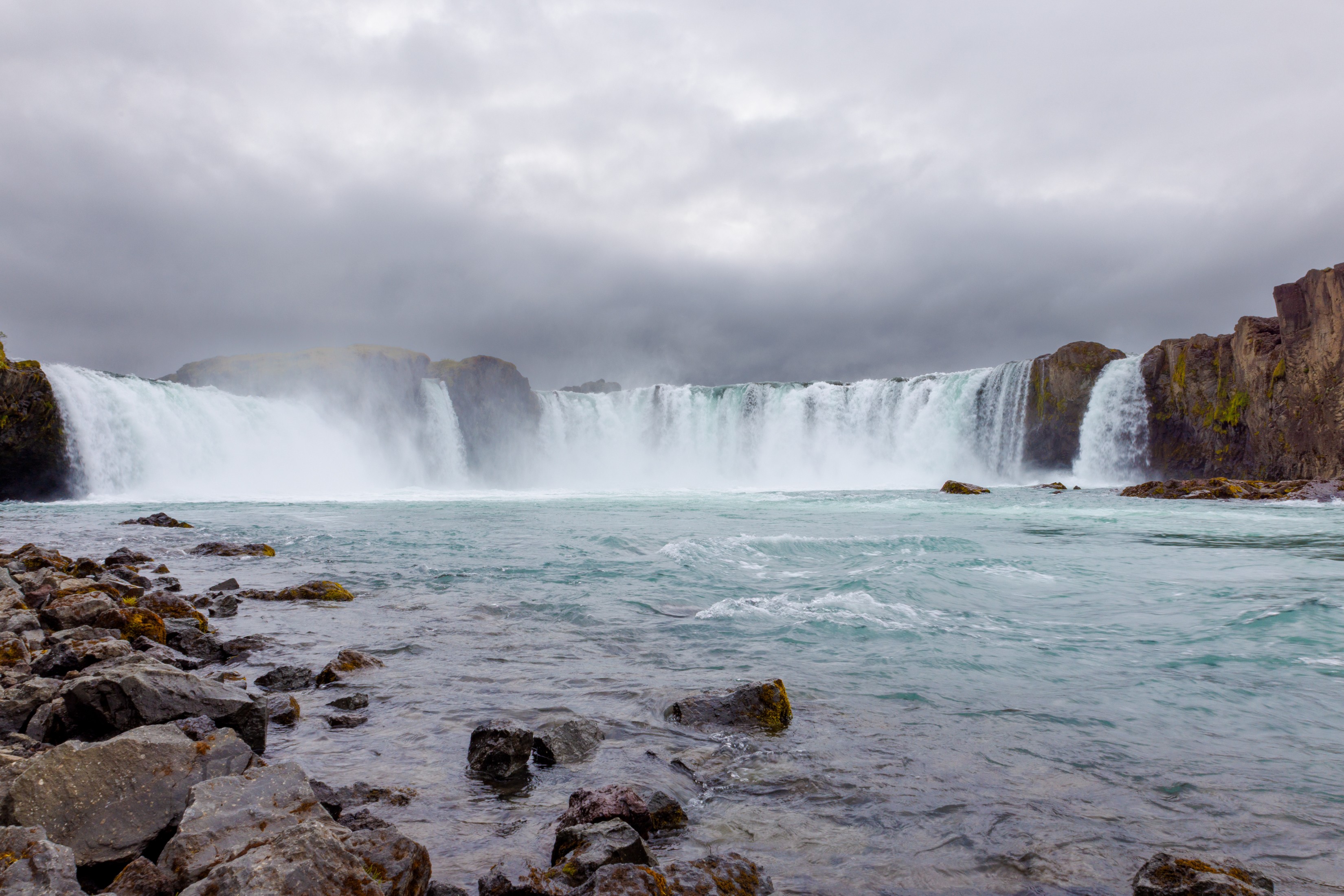Waterfall with rocks in the foreground under cloudy sky