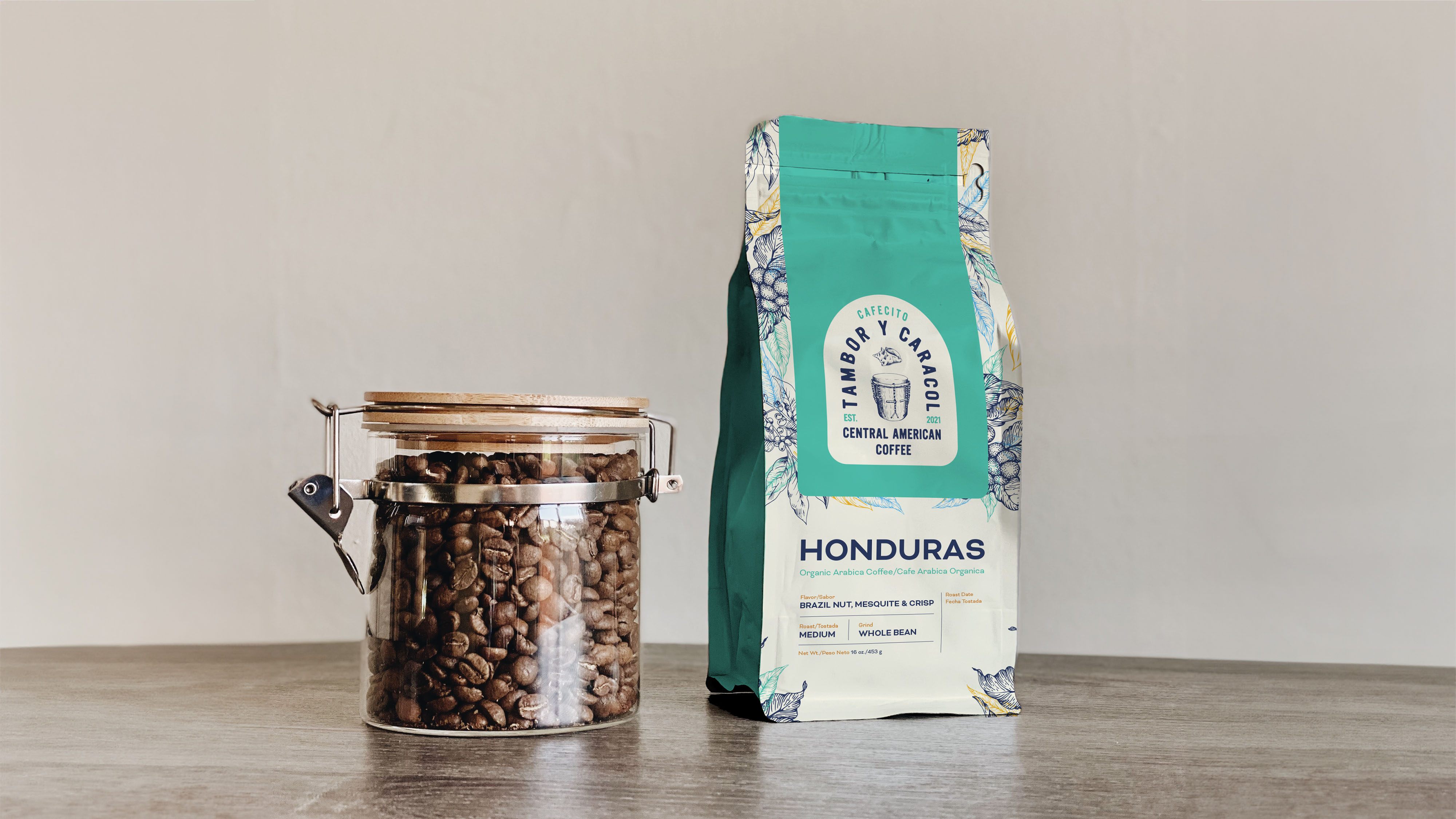 A glass jar filled with coffee beans and a bag of coffee beans on a light-colored surface.