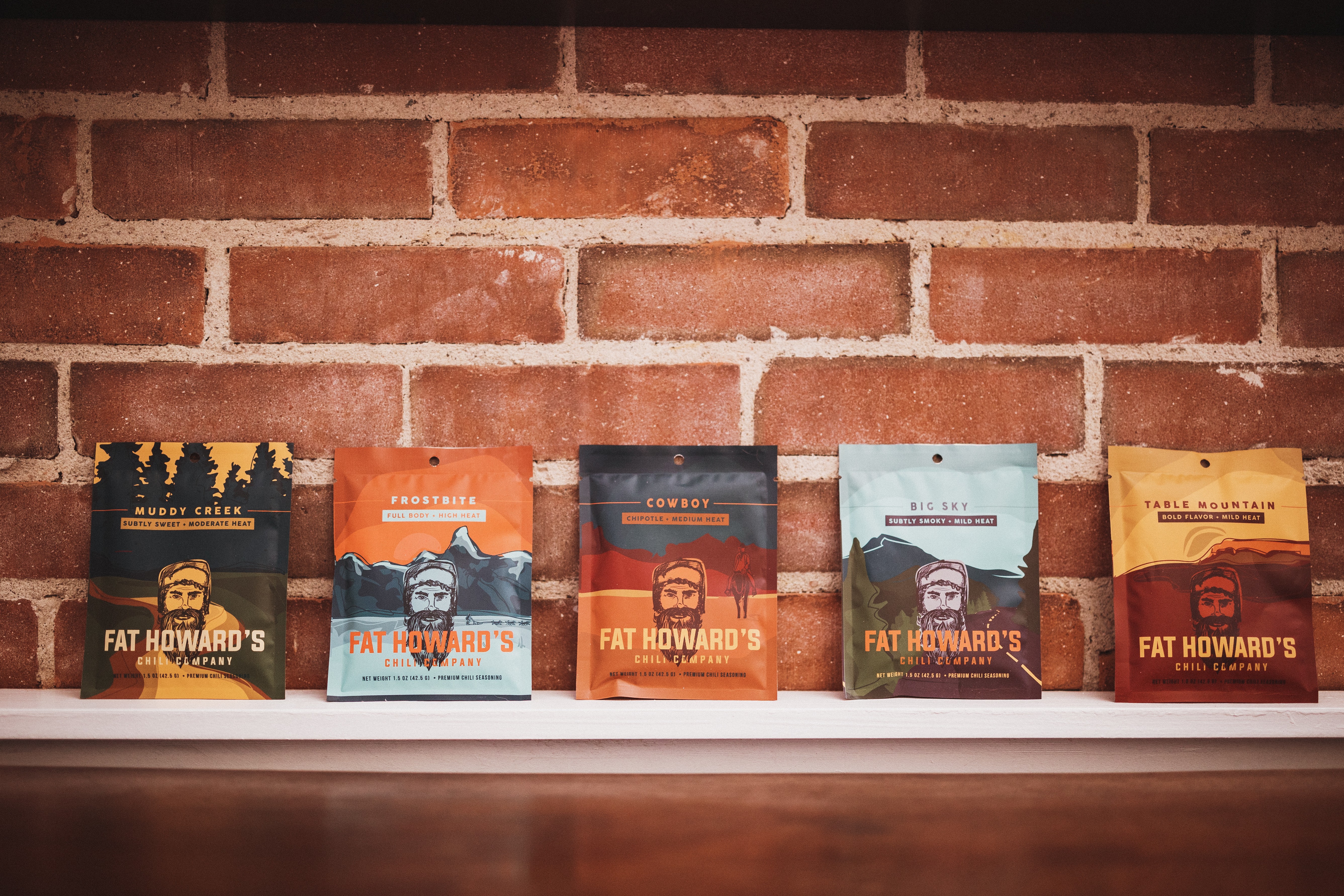 Five books on a white shelf against a brick wall, with colorful covers and titles visible.