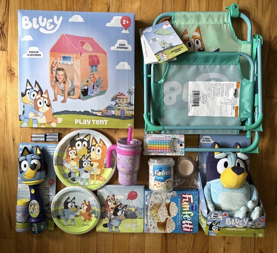 Children's play tent with Bluey theme, toys, plates, cups, and accessories on a wooden surface.