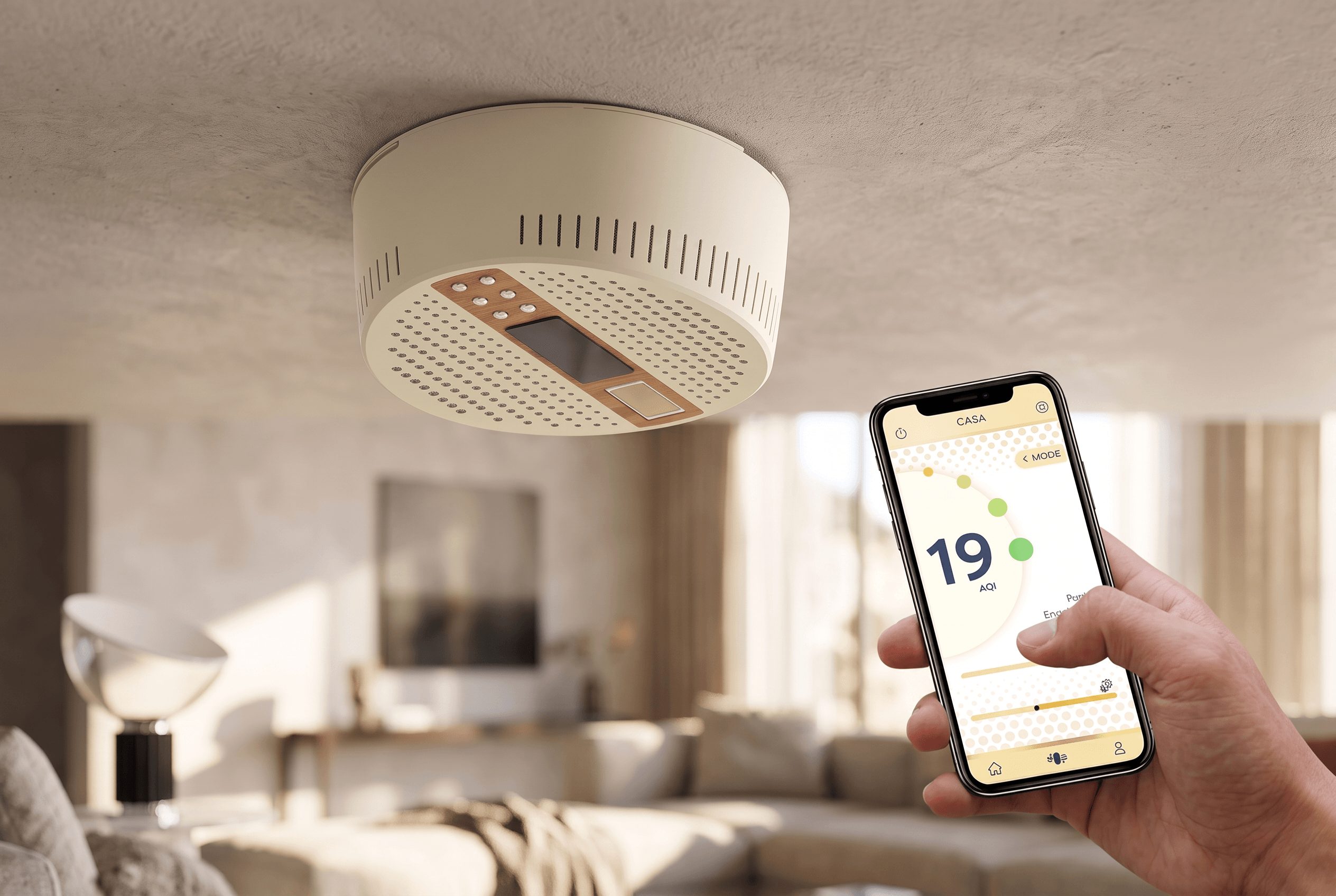 Person holding a smartphone near a ceiling-mounted device in a living room.