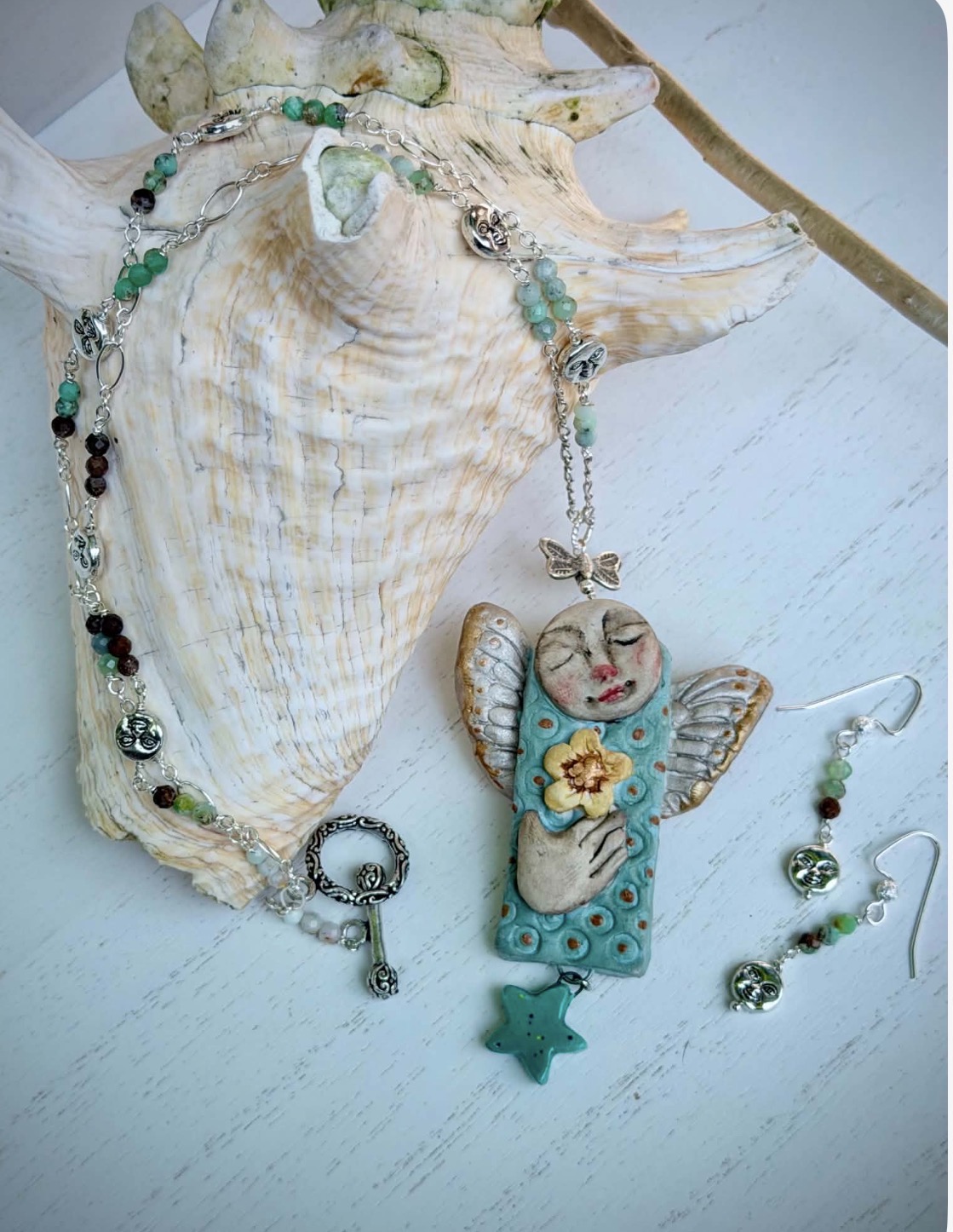 Decorative shell with jewelry and a butterfly-shaped pendant with a flower, star, and beads, on a white surface.