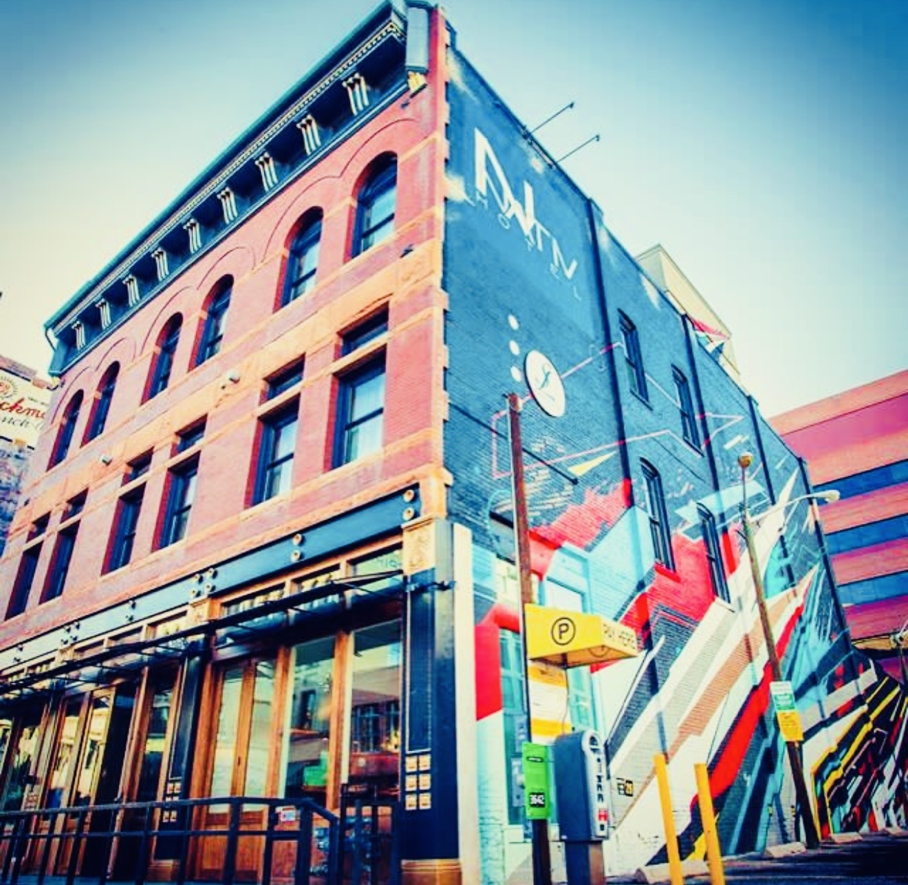 Building with colorful mural, windows, and street elements, viewed from below, bright sky background.