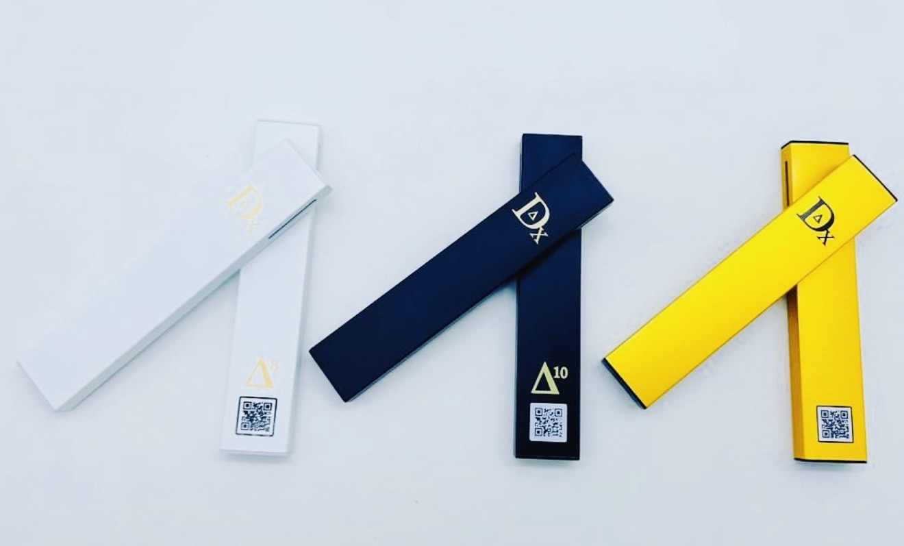 Three rectangular boxes in white, black, and yellow, with QR codes and labels, arranged on a light surface.
