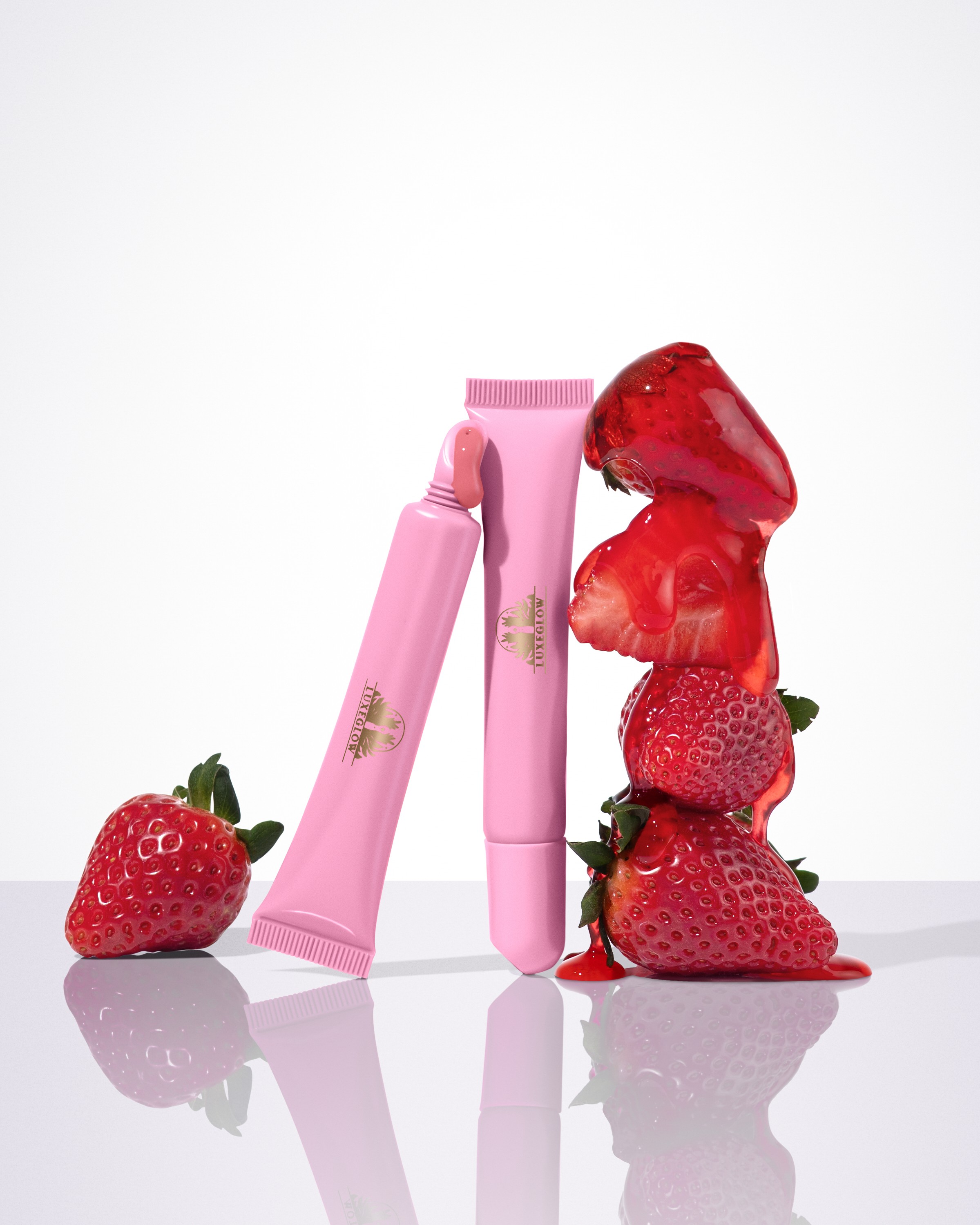 Pink lip balm tubes and fresh strawberries with strawberry jam on a reflective surface, white background.