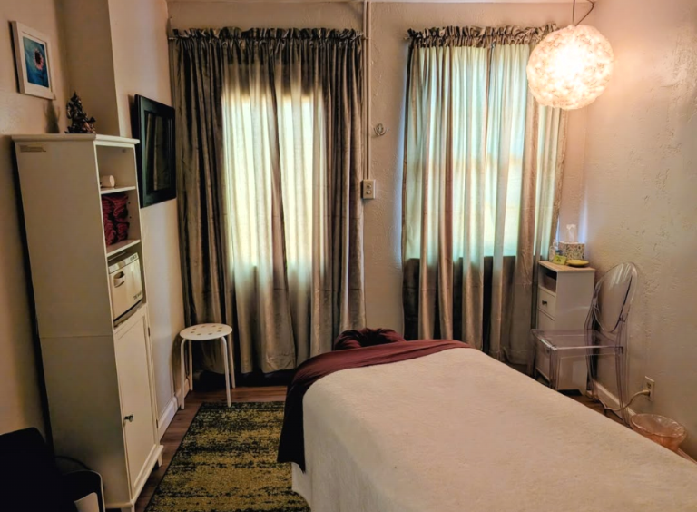 Bedroom with bed, two windows with curtains, a white shelf, and a hanging light fixture.