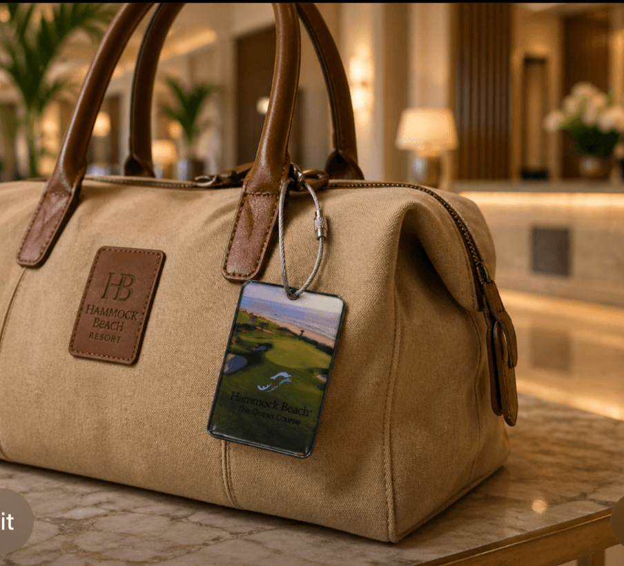 Beige handbag with brown handles and a phone attached, placed on a marble surface in a hotel lobby.