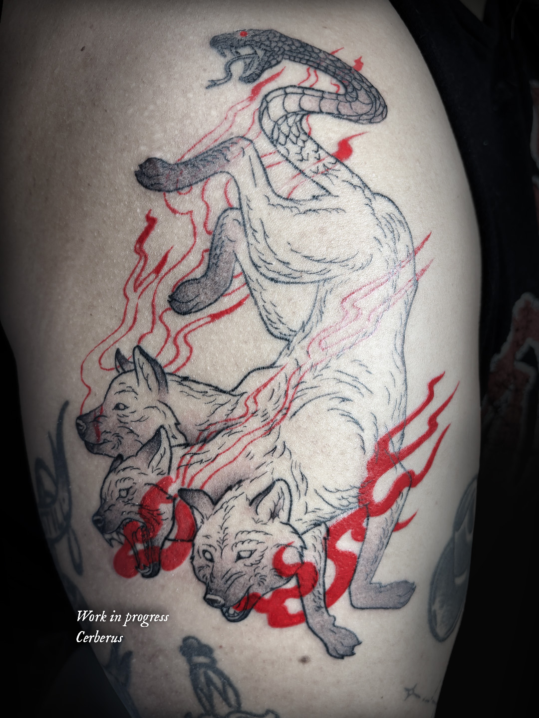 Tattoo of a snake and three wolves with red flames, with text 'Work in progress' and 'Cerberus'.
