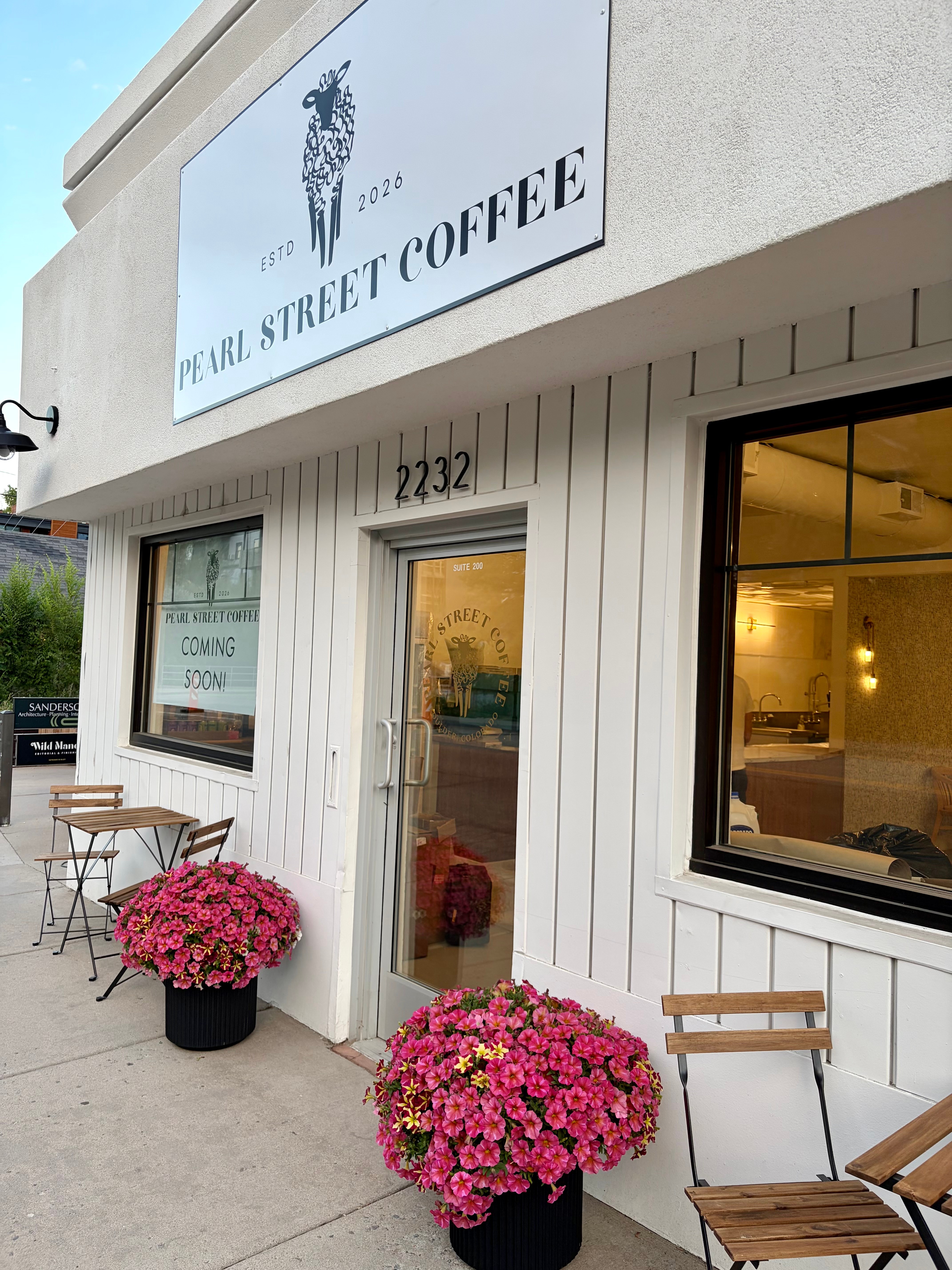 Coffee shop with pink flowers outside, window, door, and sign reading 'Pearl Street Coffee'.