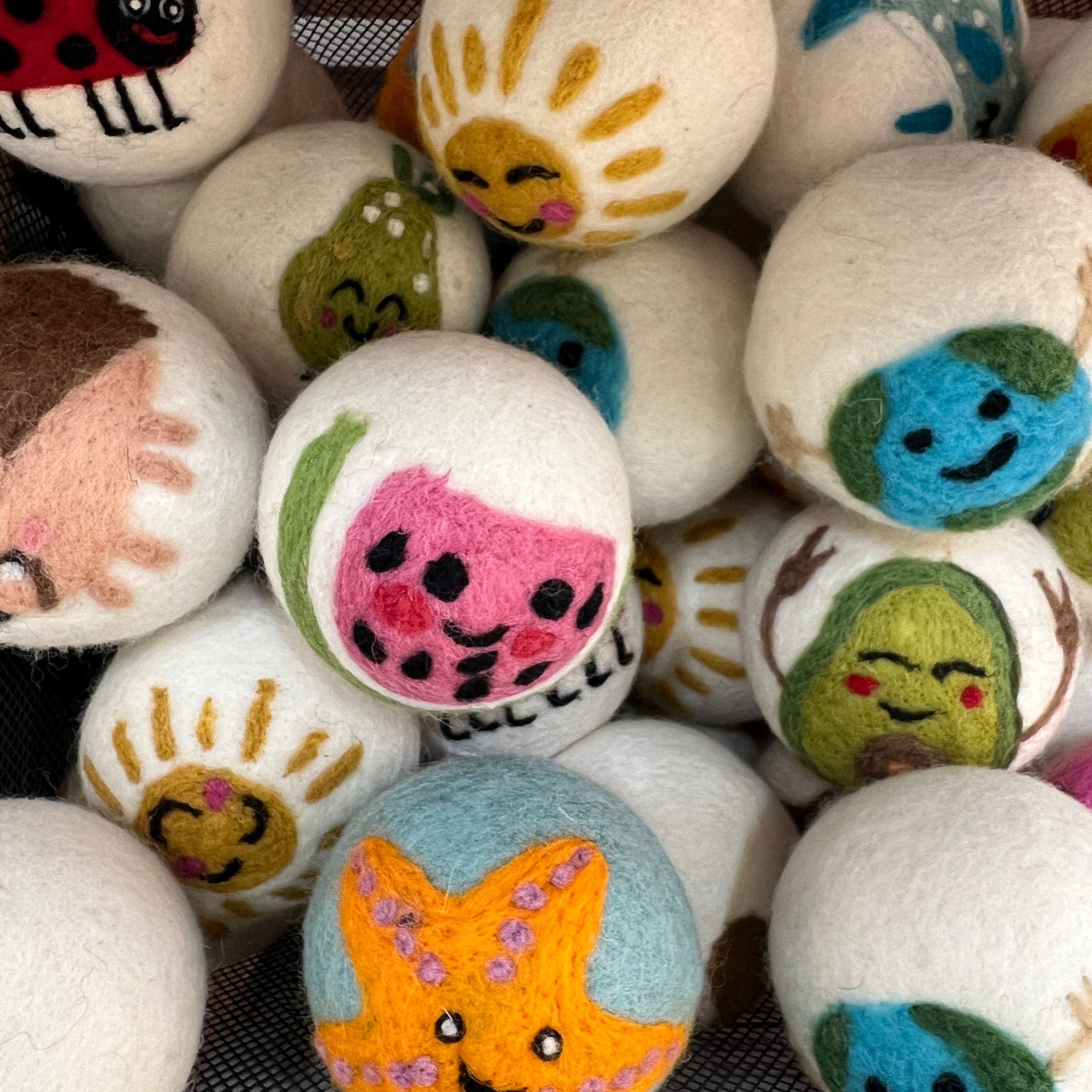 Colorful decorated balls with various faces and designs, some resembling animals or characters, piled together.