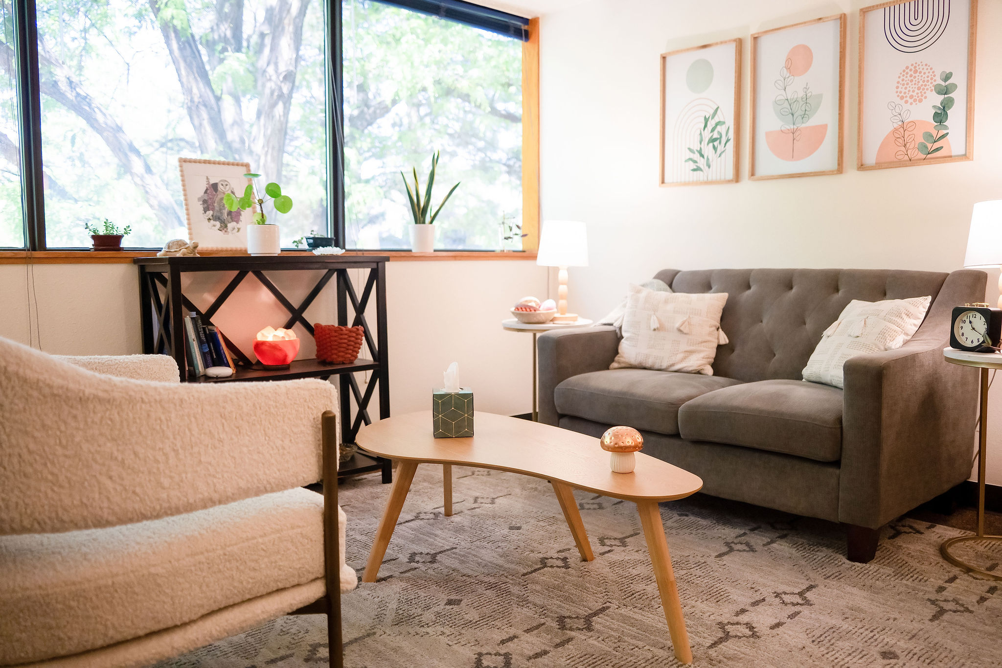 Living room with a window, sofa, armchair, coffee table, and wall art, bright and cozy atmosphere.