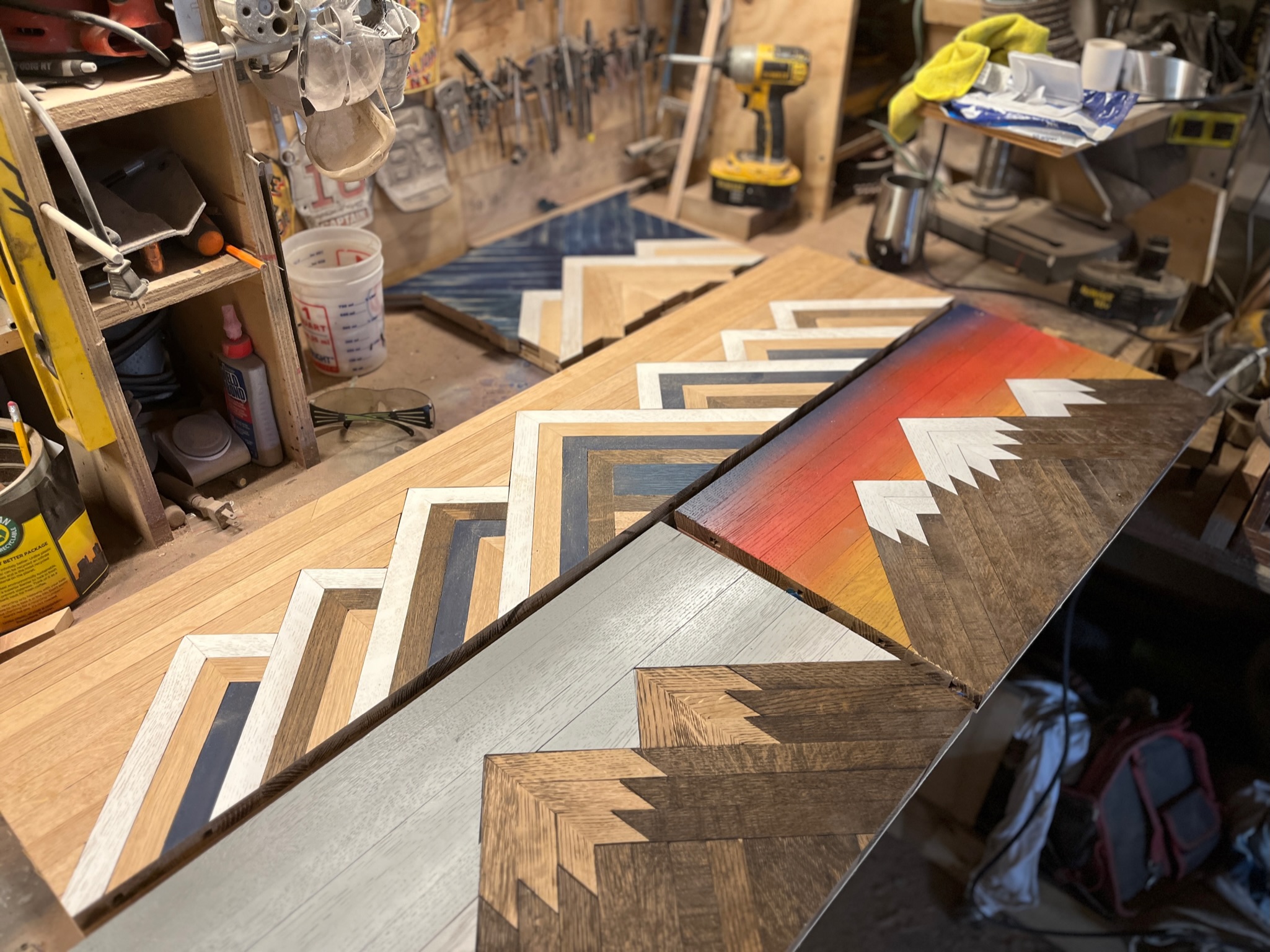 Wooden stairs with painted and natural wood finishes in a workshop, surrounded by tools and supplies.
