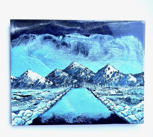 Snow-capped mountains with a pathway leading towards them, under a cloudy sky, in shades of blue and white.