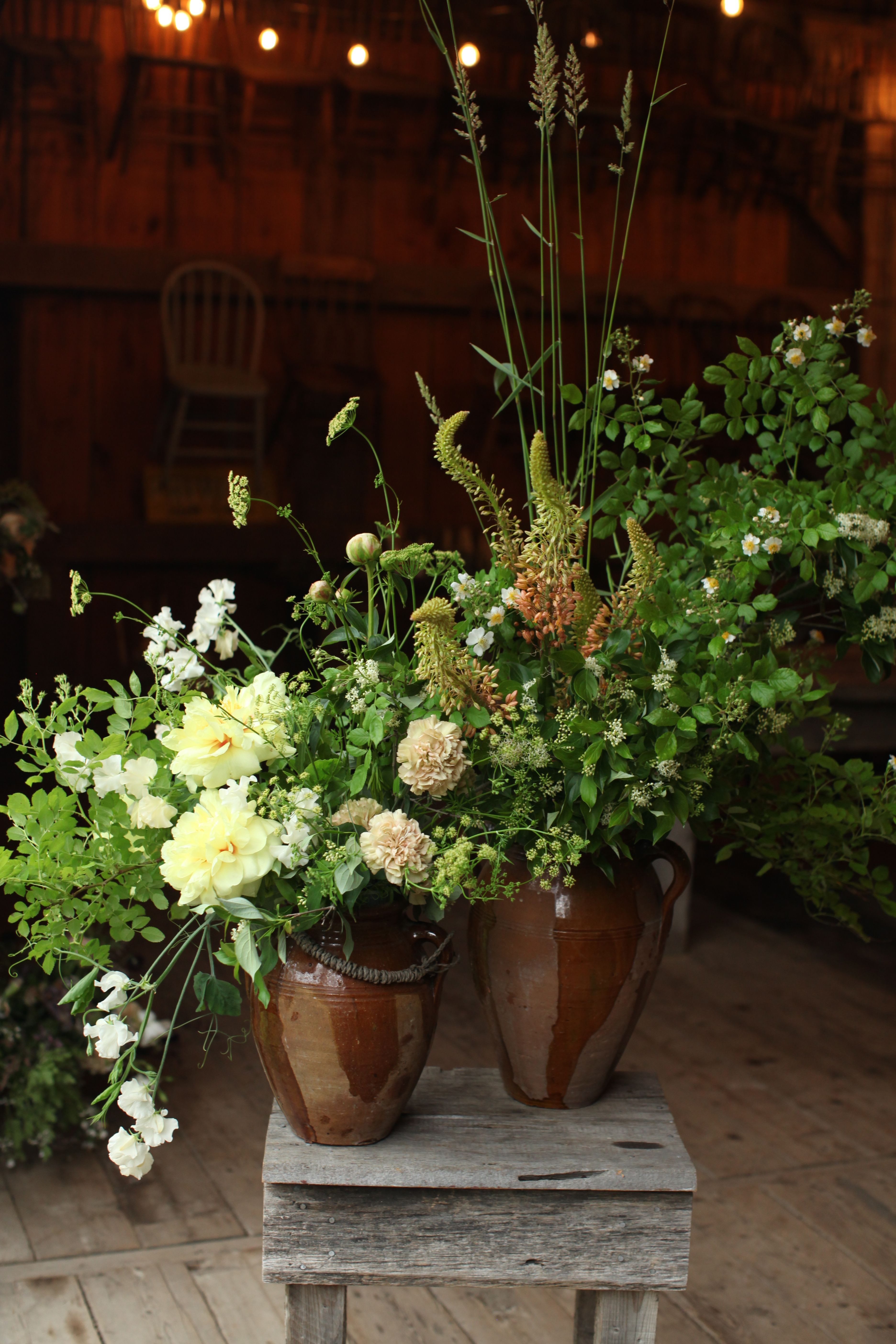 Flower arrangement with white and green flowers on a wooden surface, background of warm indoor lighting.