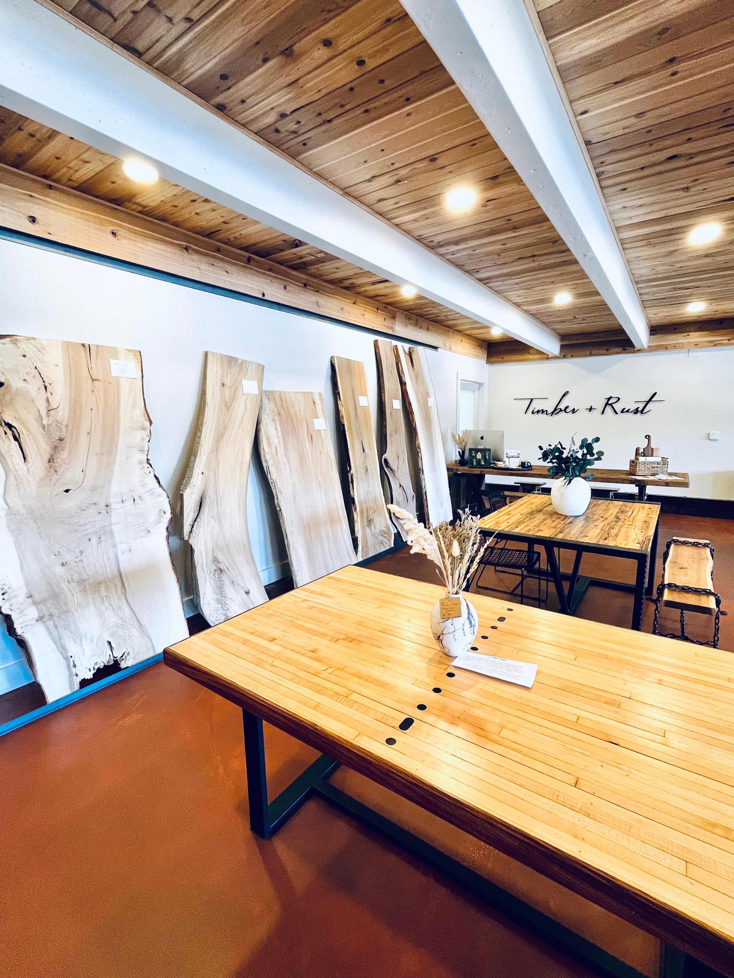 Wooden table with a small plant and a book, interior with wooden ceiling and large wood slabs on the wall.