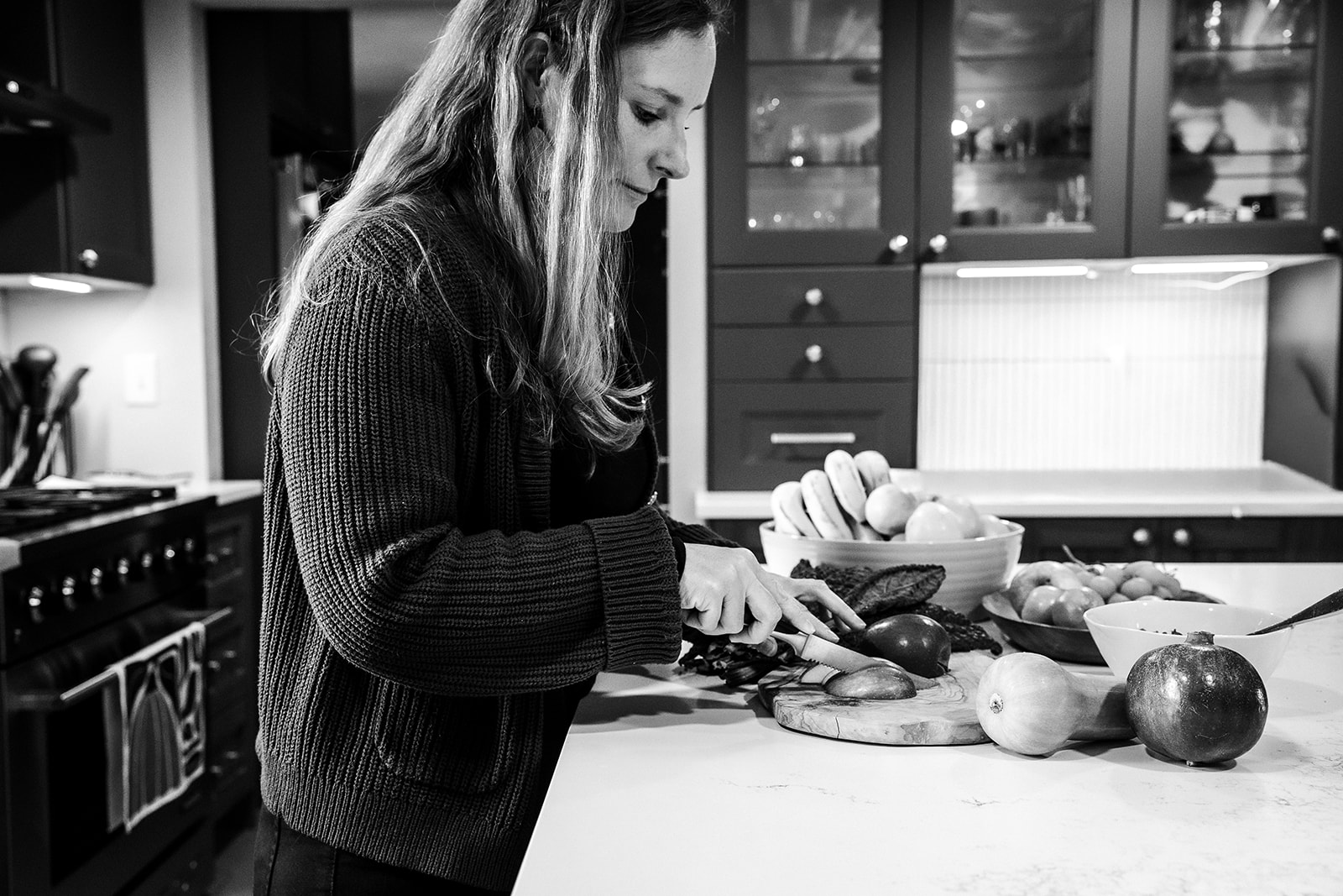 Woman preparing food in a kitchen with various vegetables on the counter.