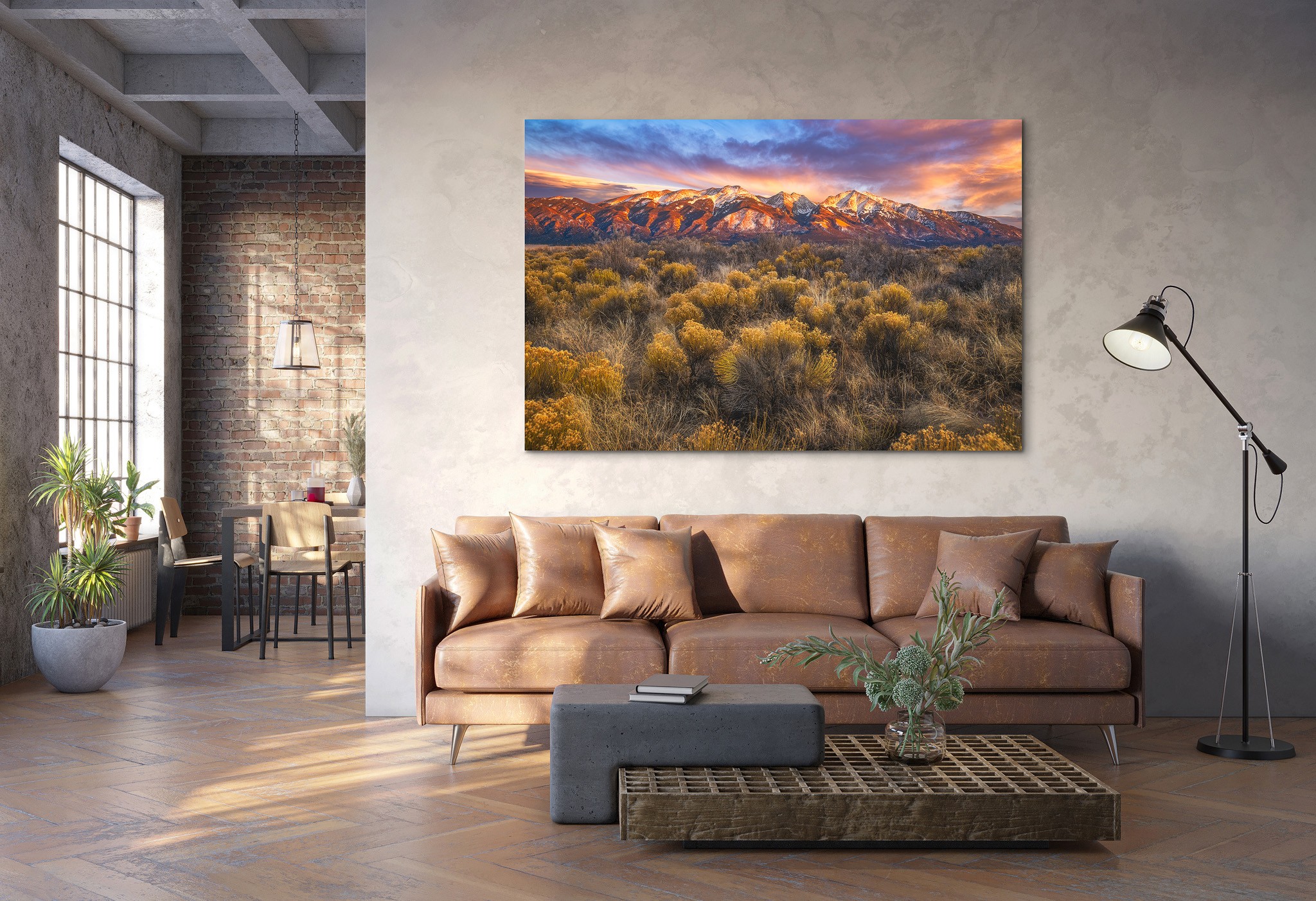 Living room with a brown sofa, a large landscape painting, and a floor lamp, with a dining area visible in the background.