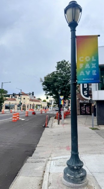 Street scene with a decorative lamppost and colorful banner, sidewalk, and buildings in the background.