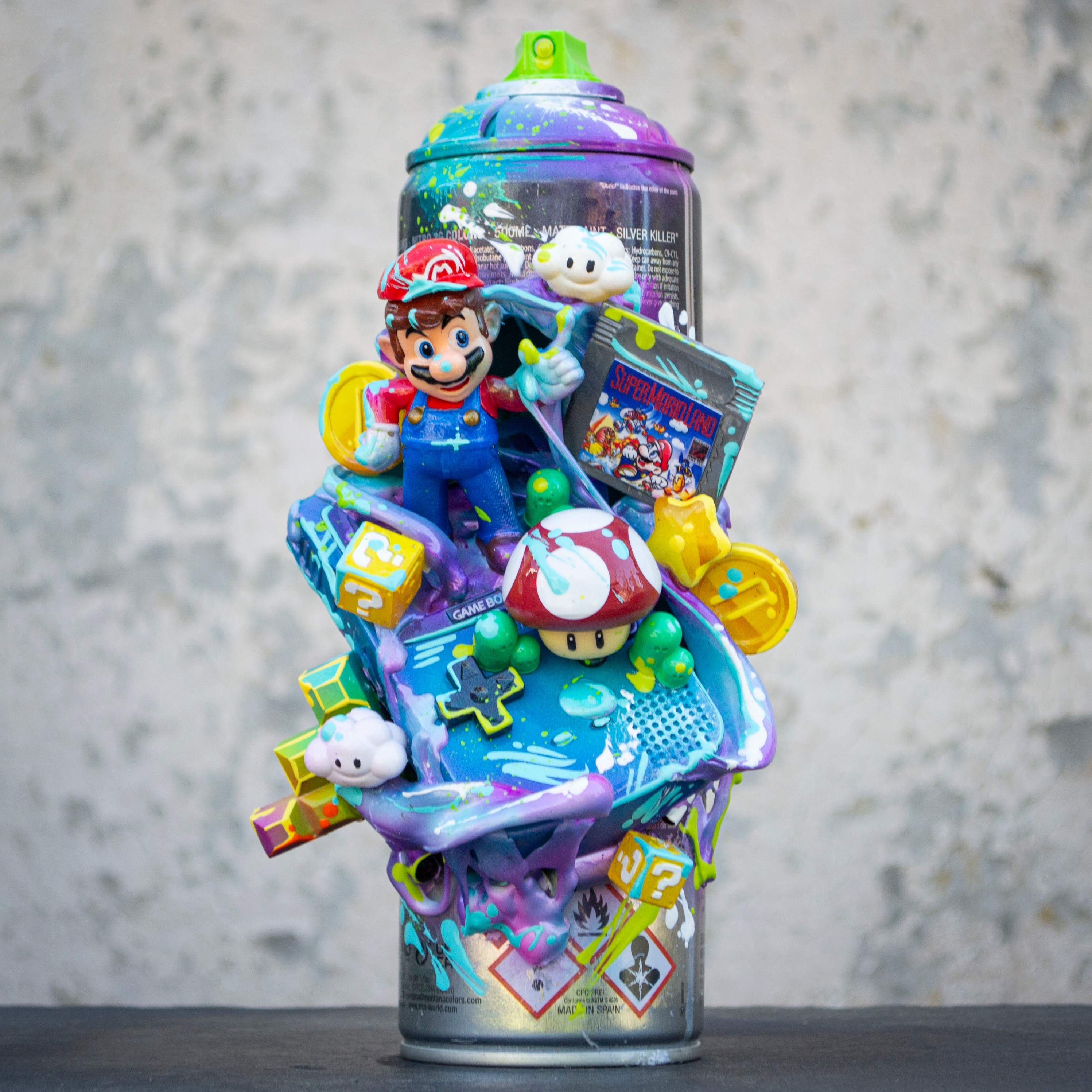 A colorful spray can with Super Mario and game-themed toys and figures on top, set against a textured background.