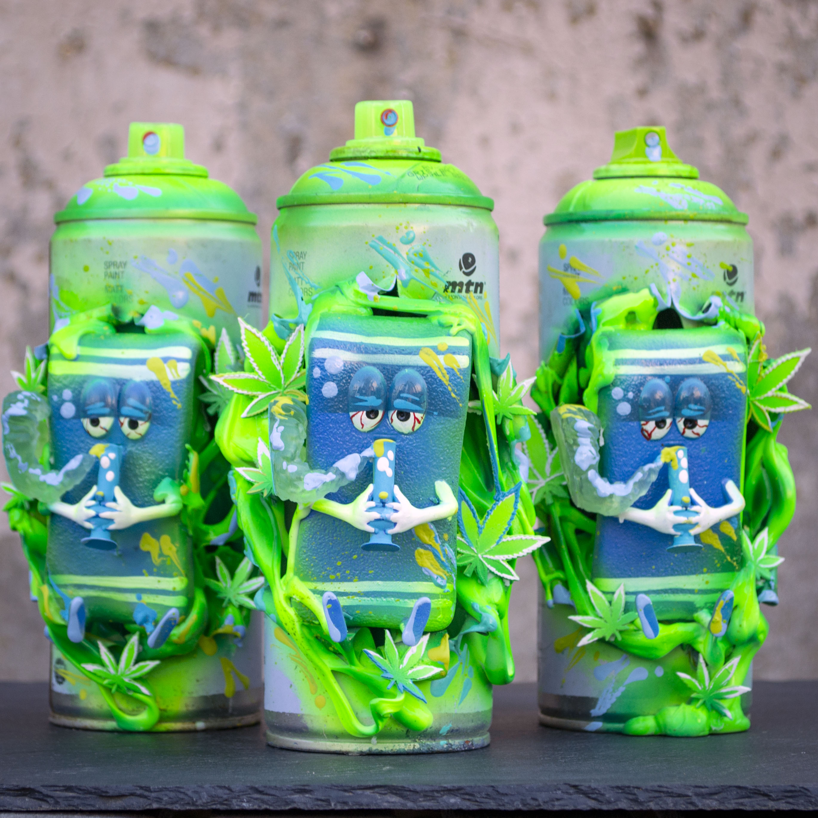 Three colorful cans with cartoon characters and green leaves, set against a textured background.