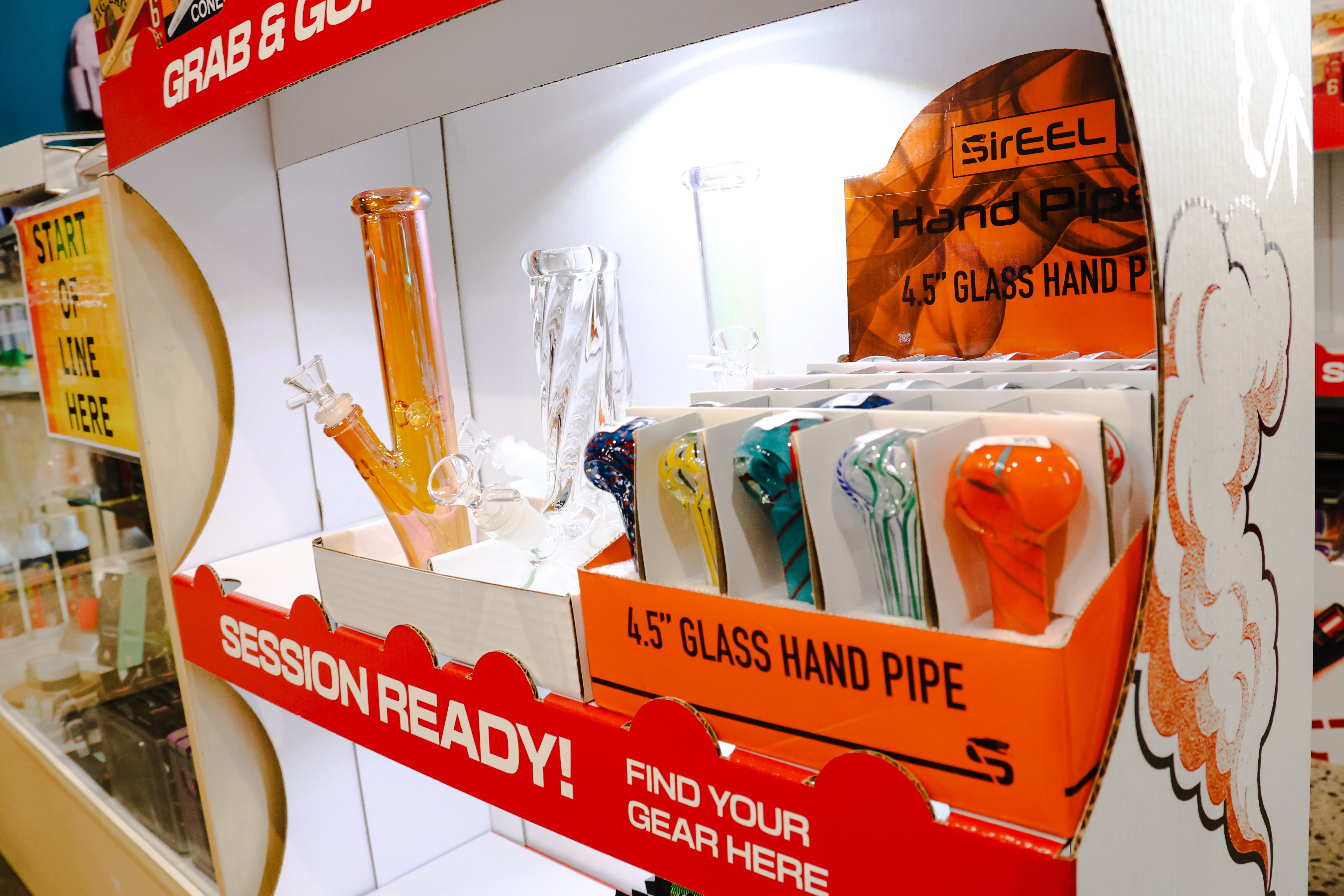 Display of 4.5-inch glass hand pipes in a store, with packaging and a sign reading 'SESSION READY!'.