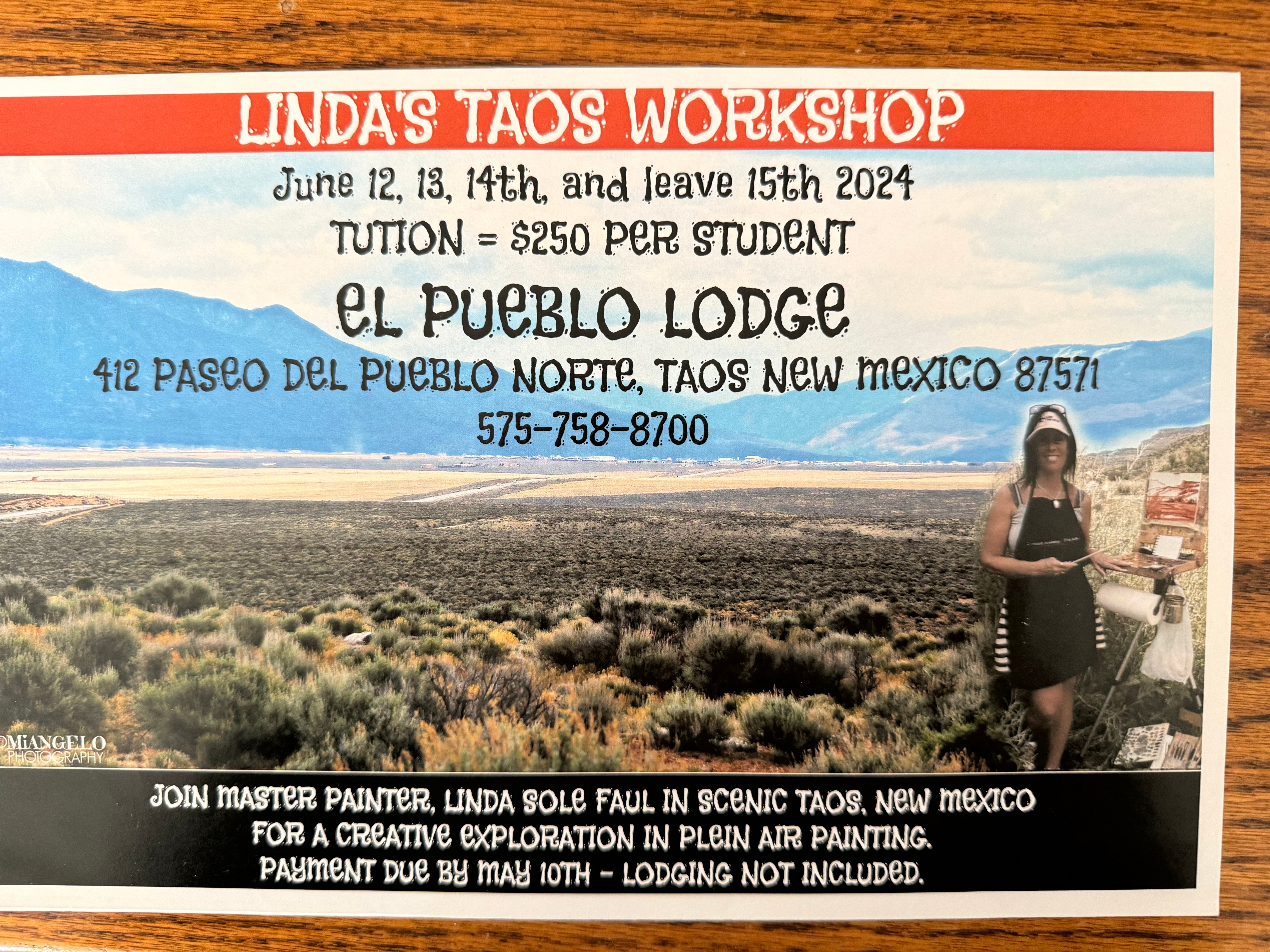 Sign for Linda's Taos Workshop with a person standing outdoors, desert landscape, and blue sky background.