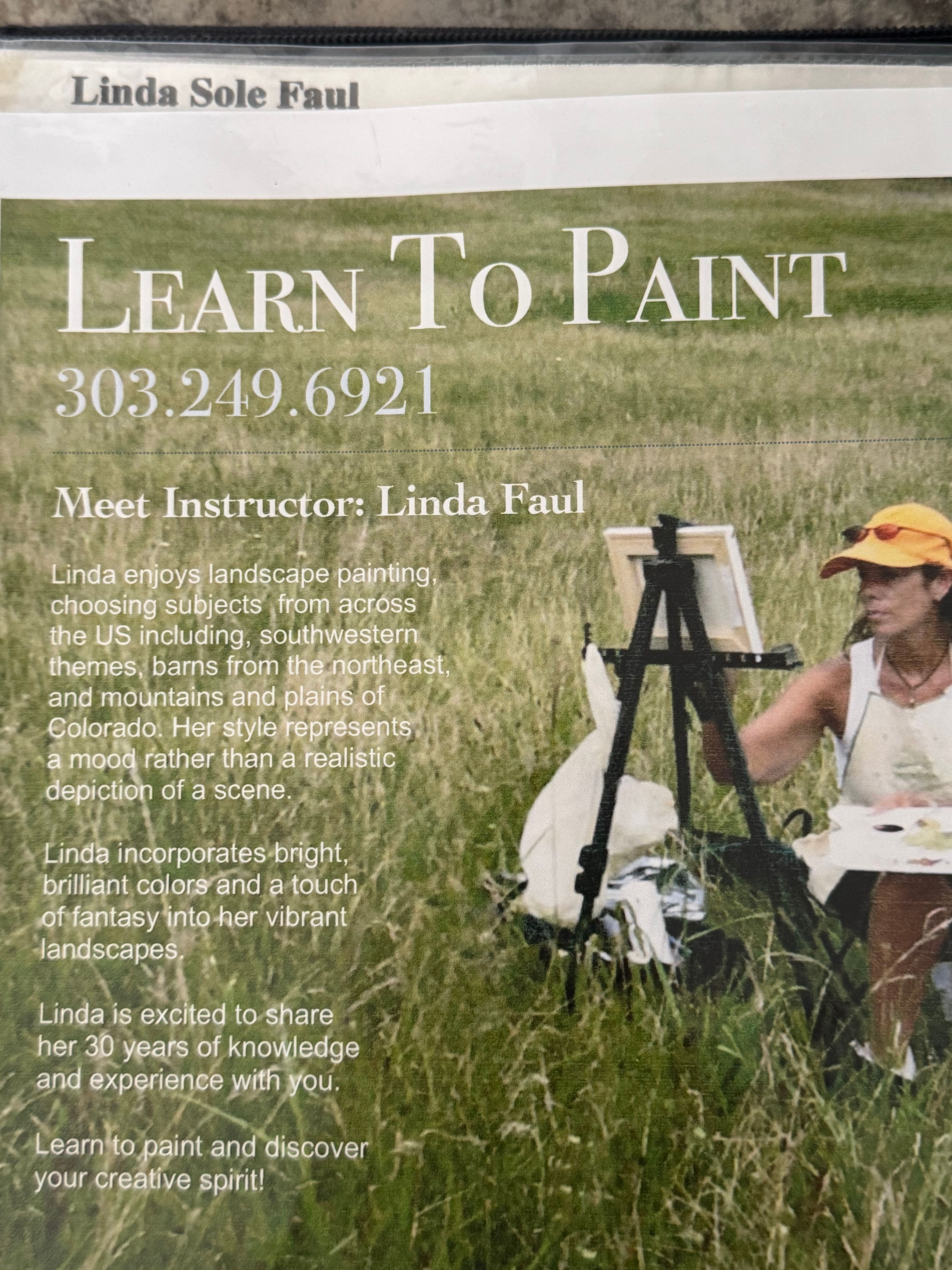 Person painting outdoors on grass with painting supplies, trees in background, and a white cloth on the ground.