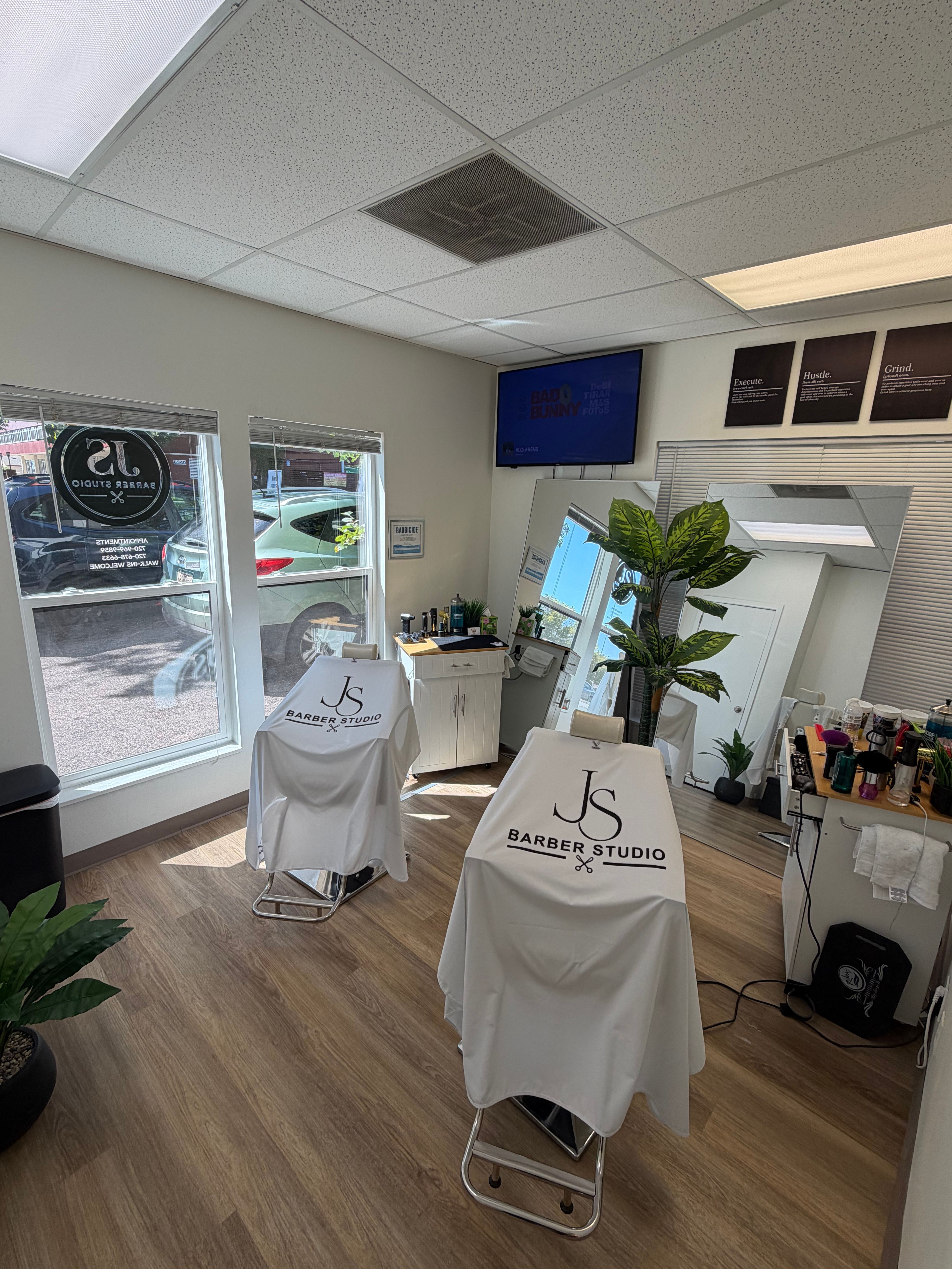 Interior of a salon with chairs covered in white cloth, plants, and a window showing outside view.