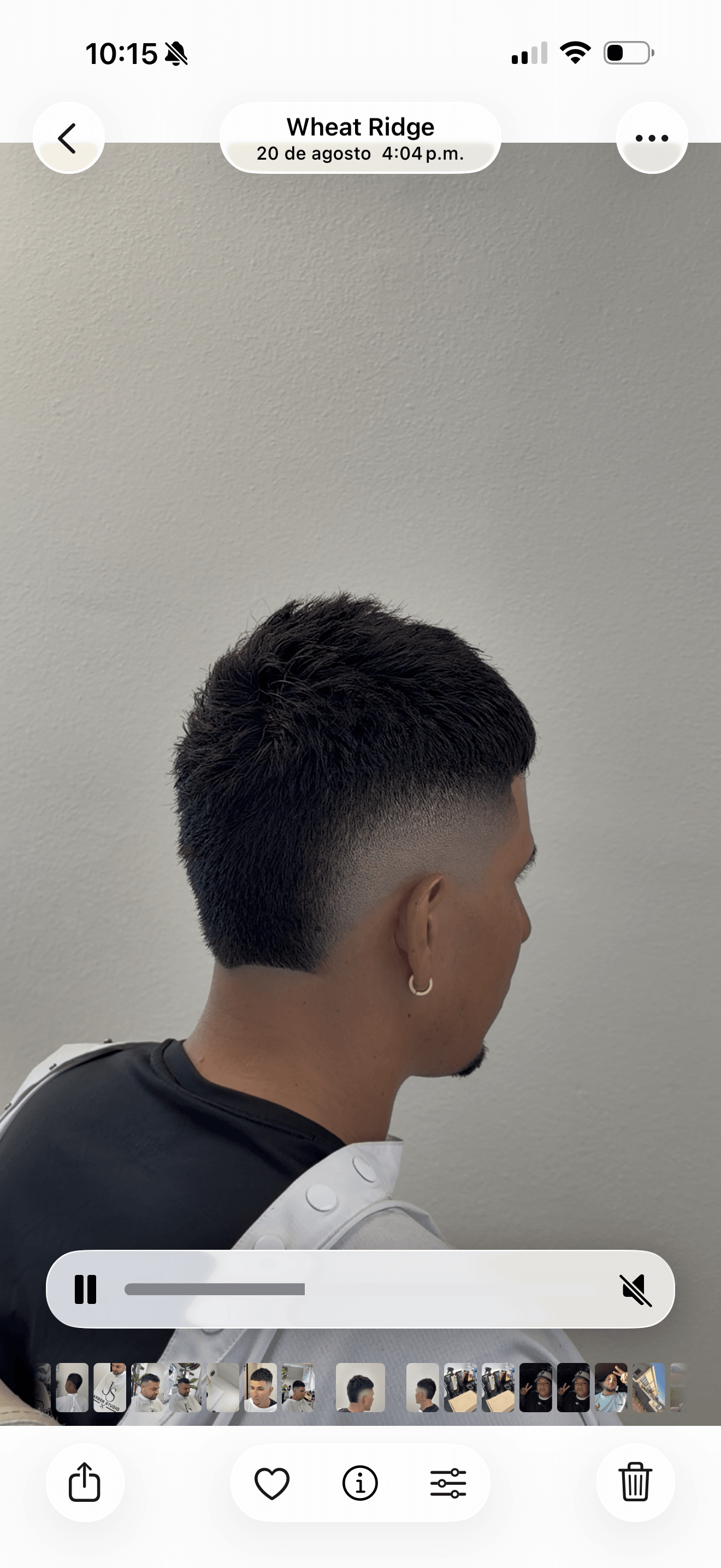 Side view of a person with short, dark hair and earrings, facing right, against a plain background.