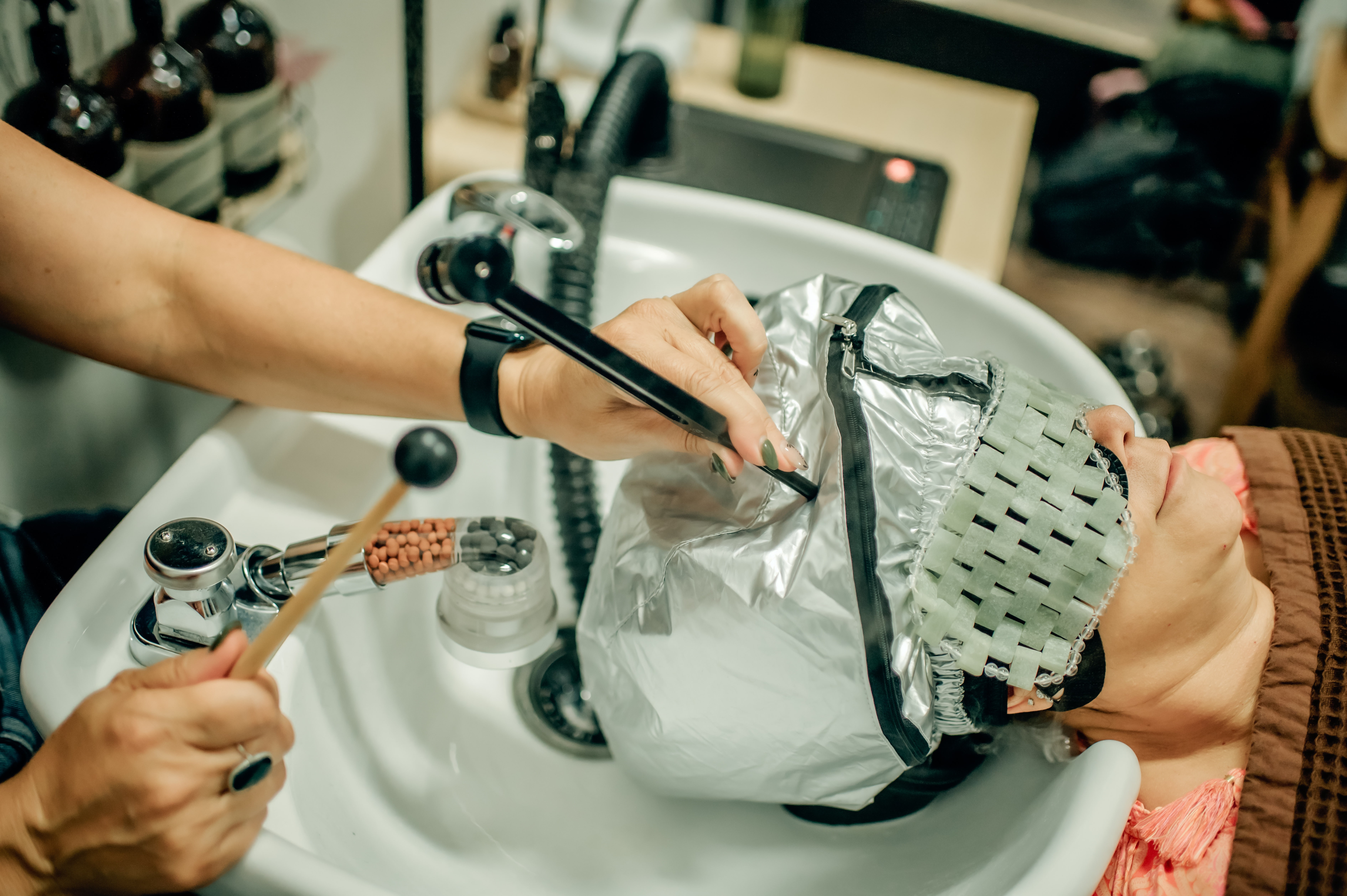 Person holding a metallic bag over a sink, with another person using a tool nearby, in a store or workshop setting.
