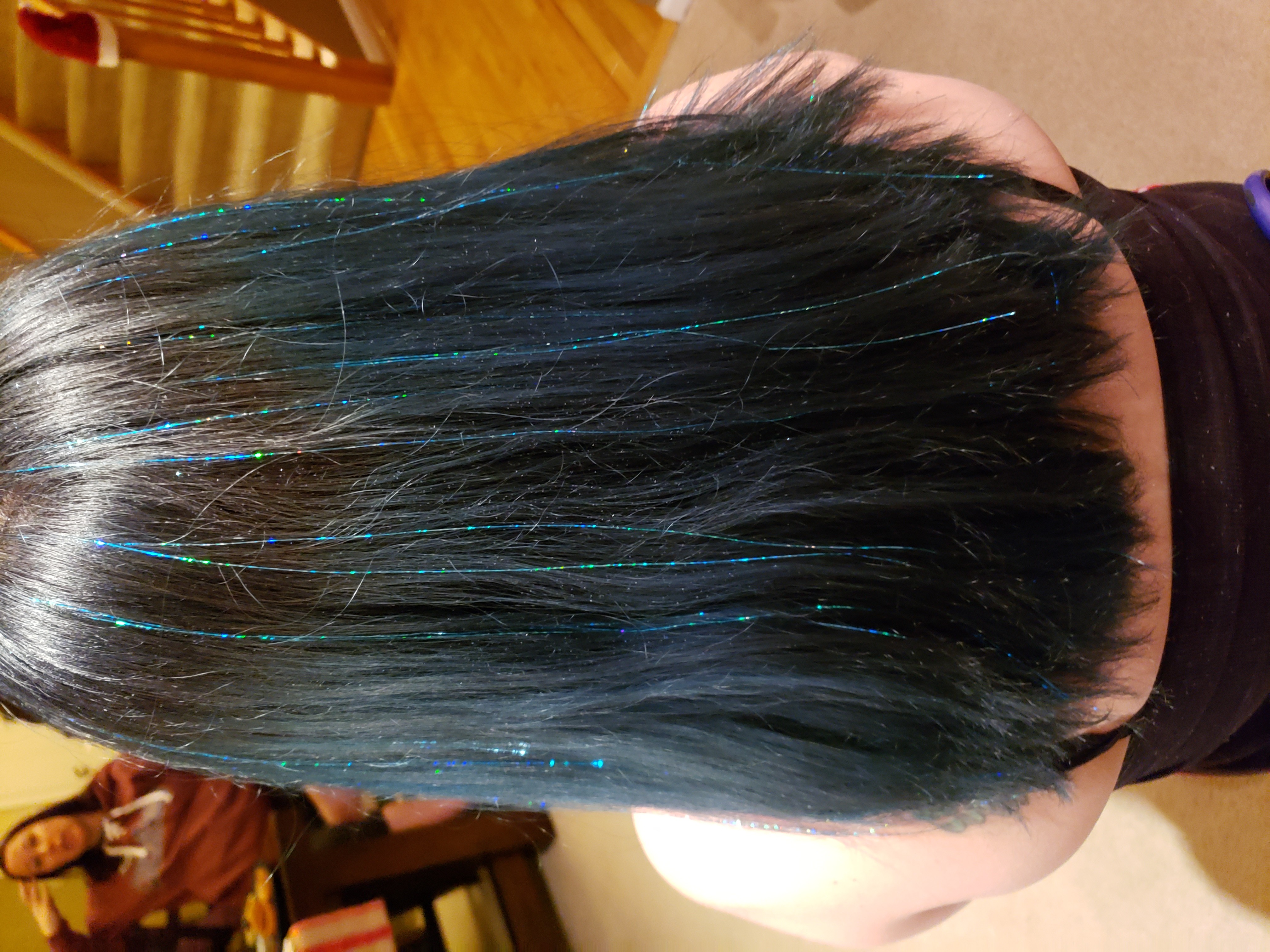 Person with straight, dark hair with blue streaks, viewed from behind, indoors.