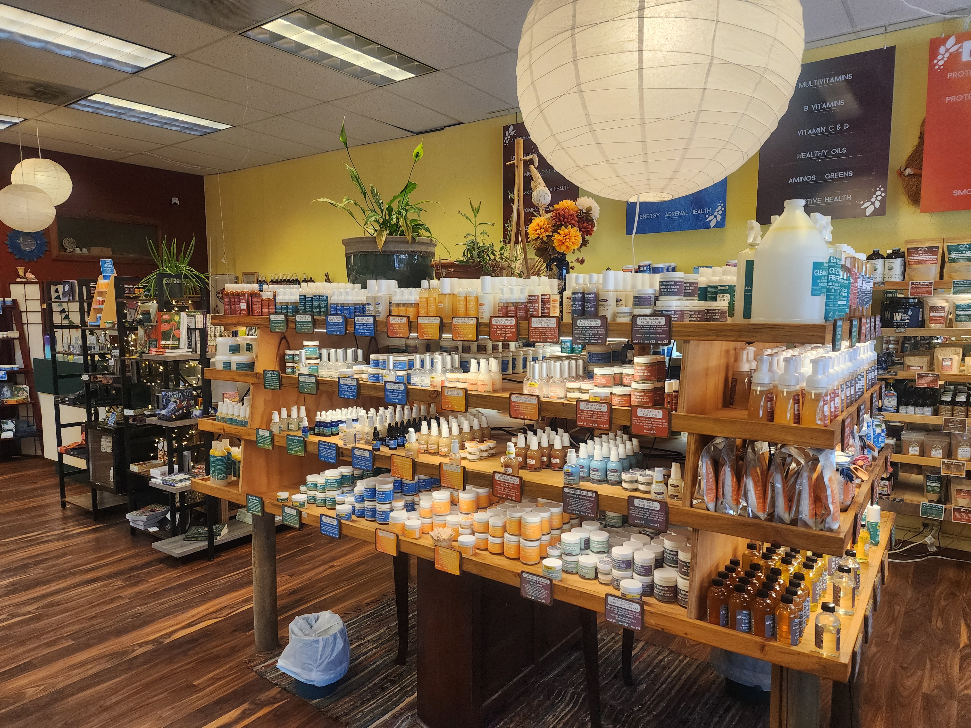 Display of various soap and skincare products on wooden shelves in a store, with a large paper lantern overhead.