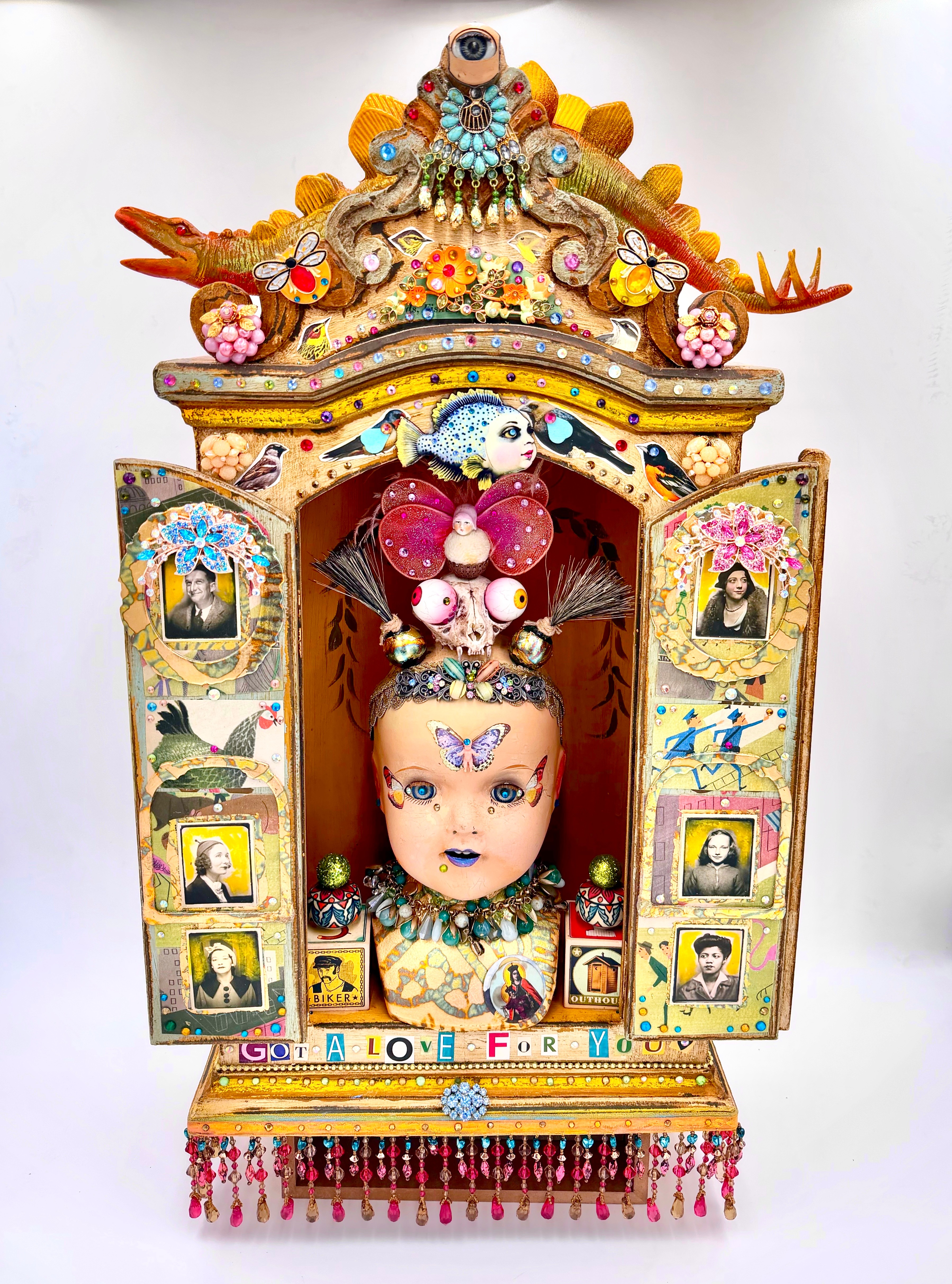 Colorful shrine with a doll, decorated with flowers, pictures, and ornaments, featuring a dragon and intricate designs.