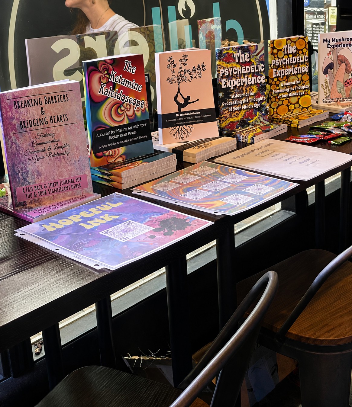 Books displayed on a table with colorful covers, some standing upright and others lying flat, in a bookstore or library setting.