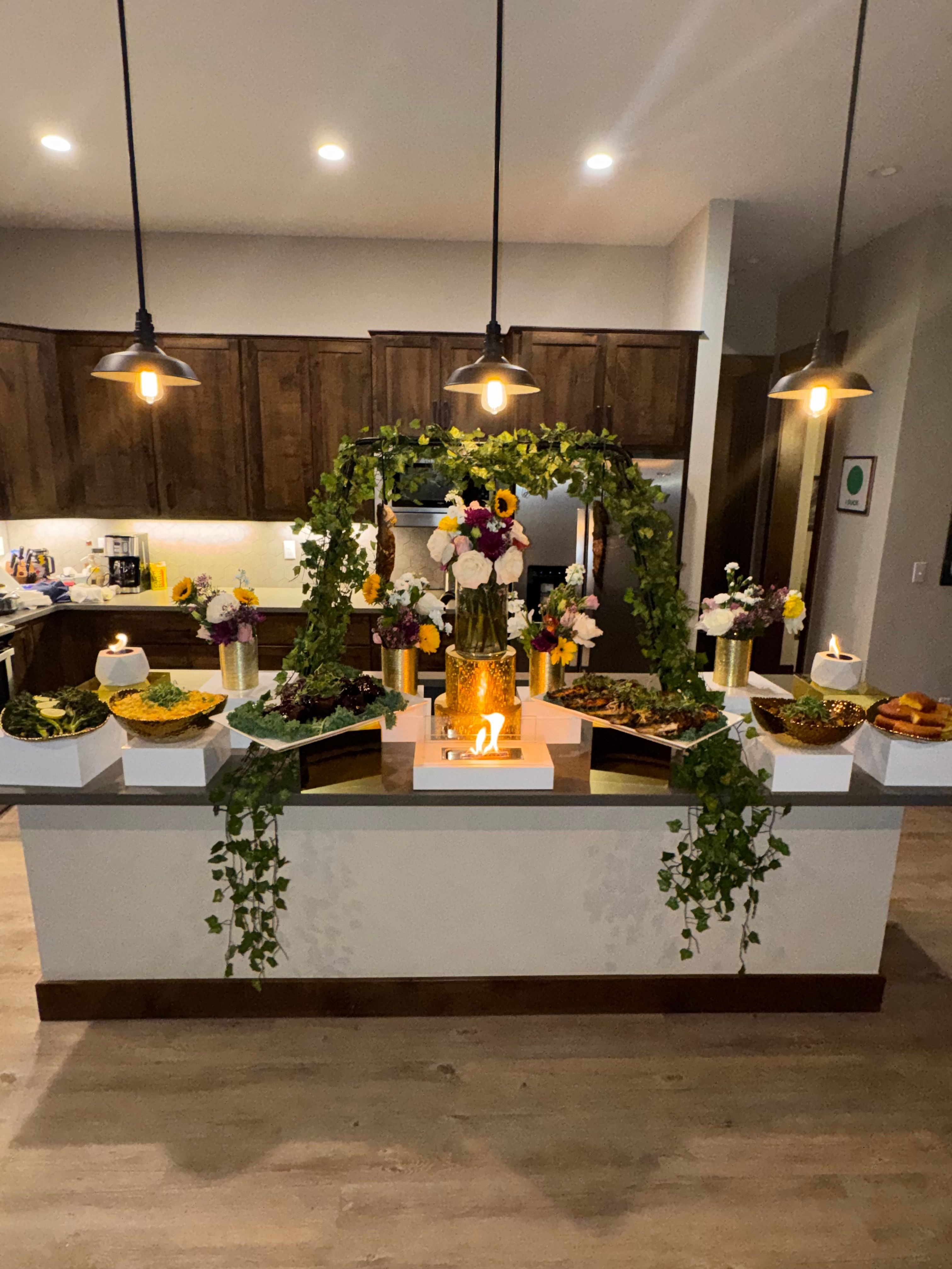 Decorative table with candles, flowers, and greenery in a modern room, with a white wall and wooden floor.
